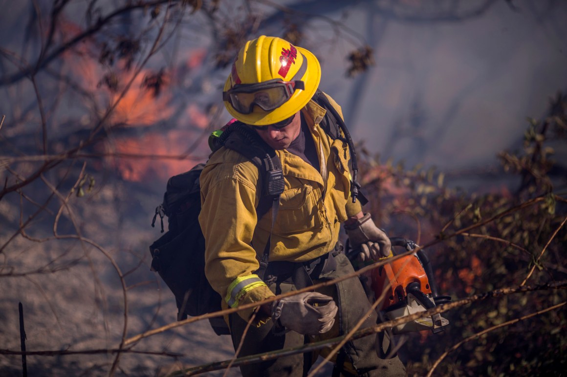 A firefighter cuts brush at the Thomas Fire on December 7th, 2017, near Fillmore, California. Strong Santa Ana winds are pushing multiple wildfires across the region, expanding across tens of thousands of acres and destroying hundreds of homes and structures.