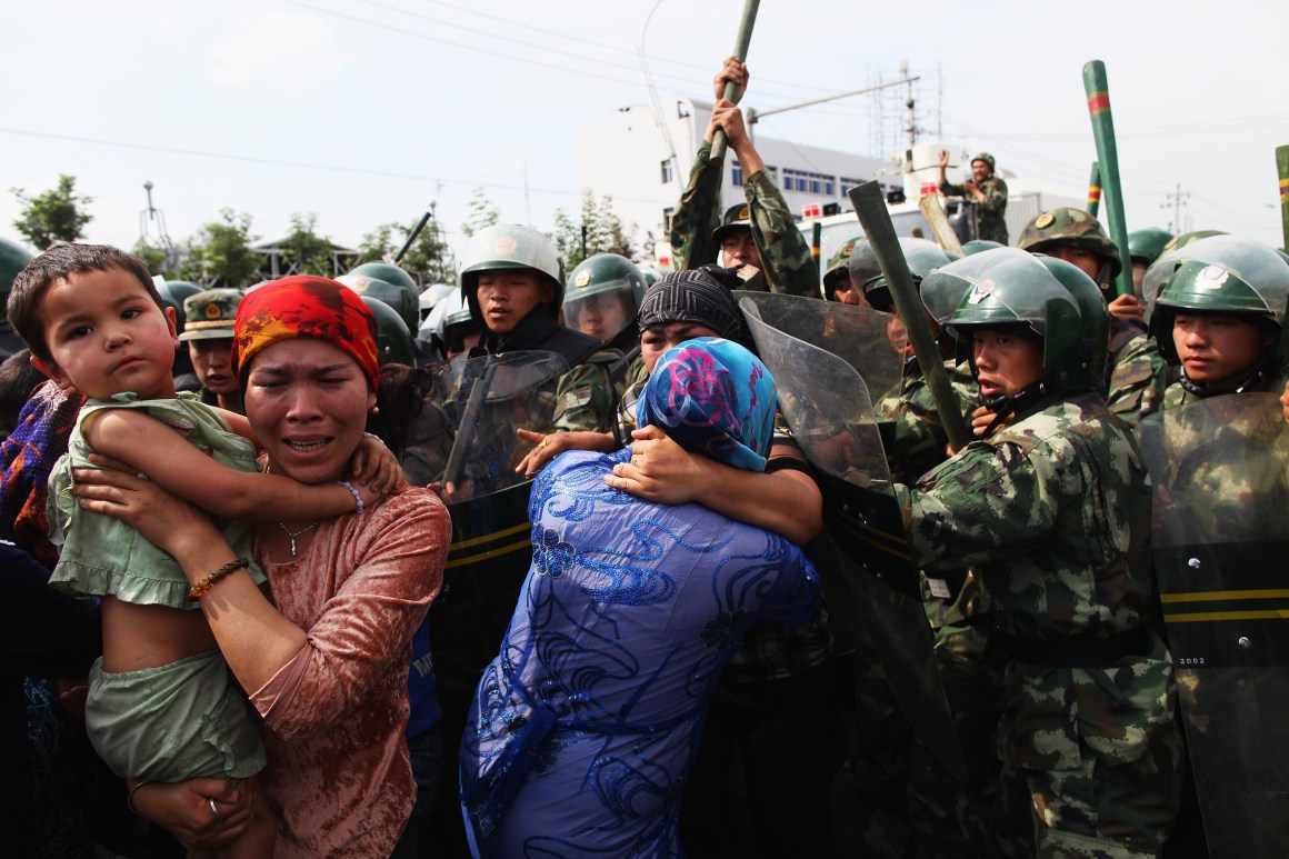 Chinese policemen push Uighur women who are protesting at a street on July 7th, 2009, in Urumqi, China.