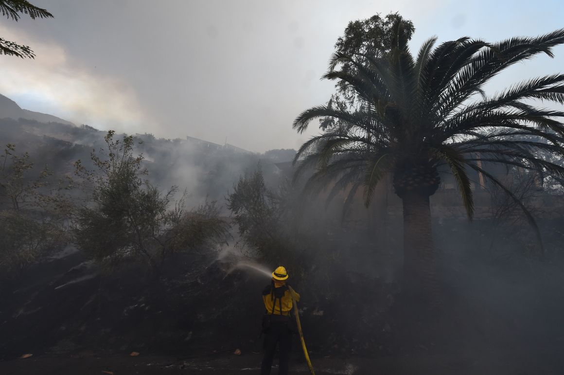 A firefighter puts out hotspots on a smoldering hillside in Montecito, California, as strong winds blow smoke and embers inland on December 16th, 2017.