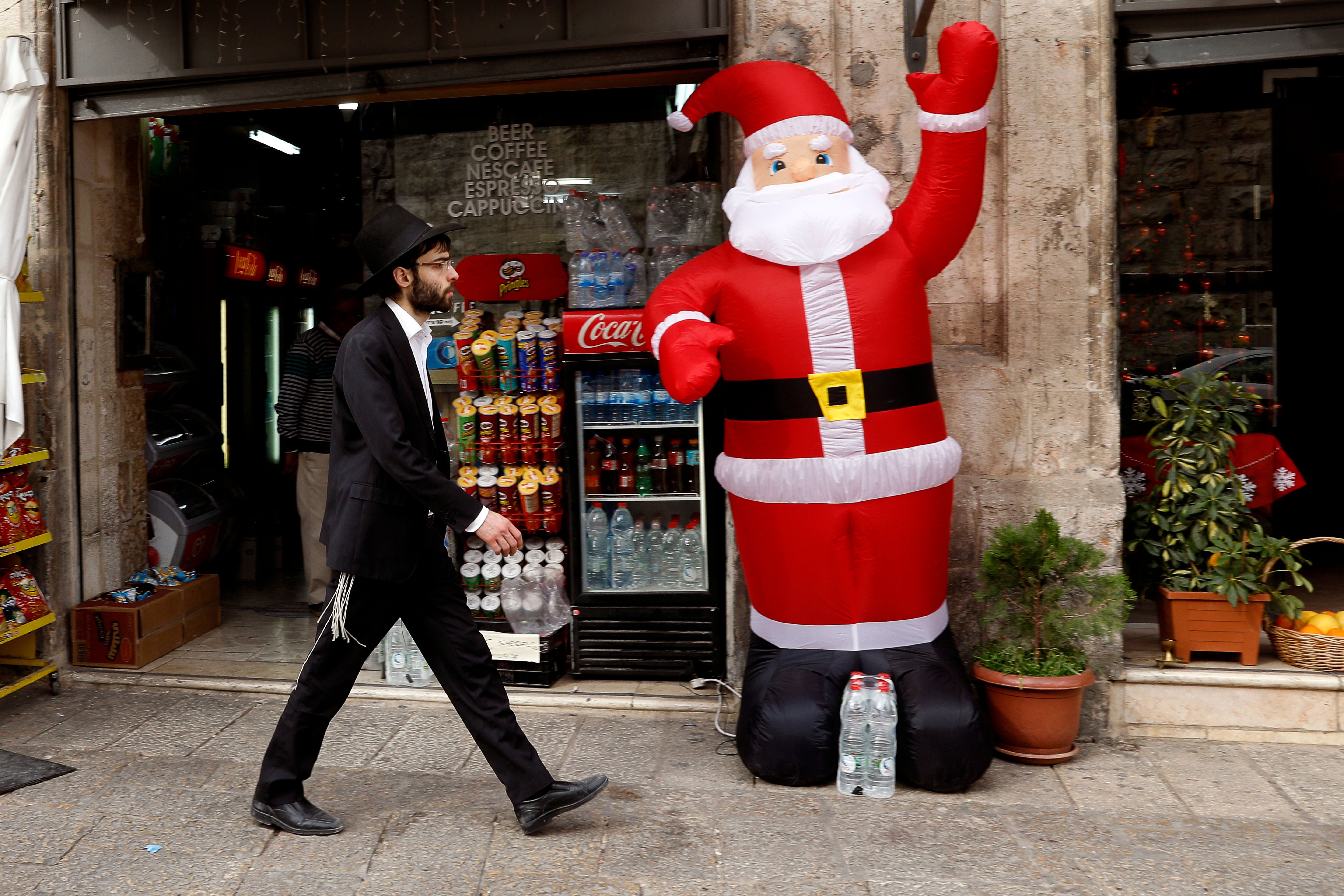 An orthodox Jewish Israeli walks past an inflatable figure of Santa Claus in the Christian Quarter of Jerusalem on December 20th, 2017.