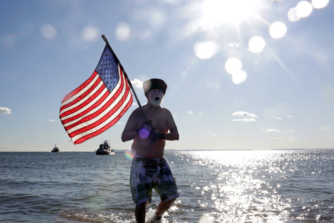 A Polar Bear Club swimmer carries an American flag as the group makes its annual icy plunge into the Atlantic Ocean on January 1st, 2018, on Coney Island in the Brooklyn borough of New York City.