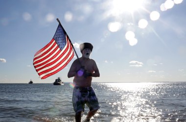 A Polar Bear Club swimmer carries an American flag as the group makes its annual icy plunge into the Atlantic Ocean on January 1st, 2018, on Coney Island in the Brooklyn borough of New York City.