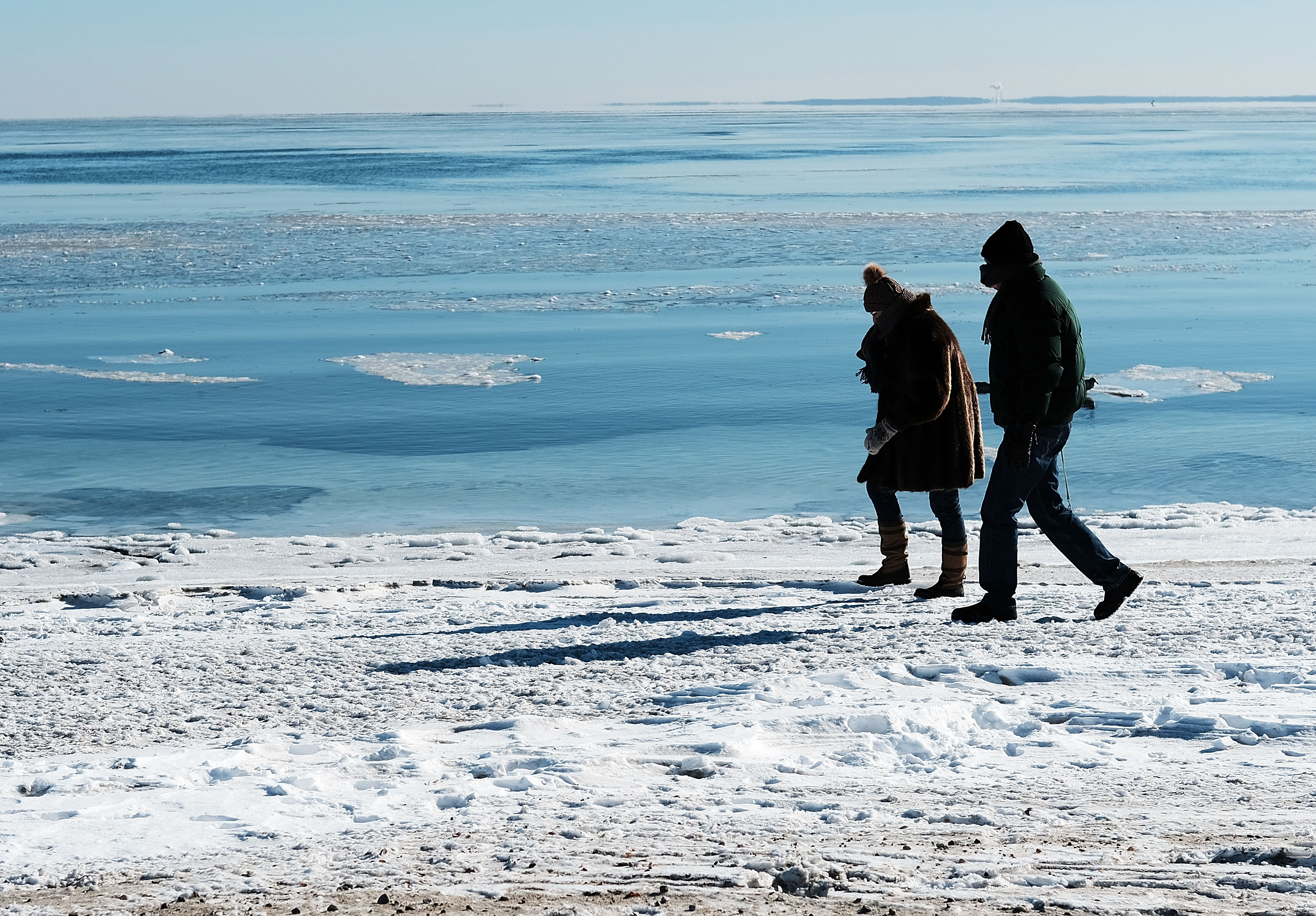 People walk along a beach covered in snow and ice in Westport, Connecticut, on January 7th, 2018. Following a heavy snowfall last week, much of New England is experiencing Arctic-like weather conditions.