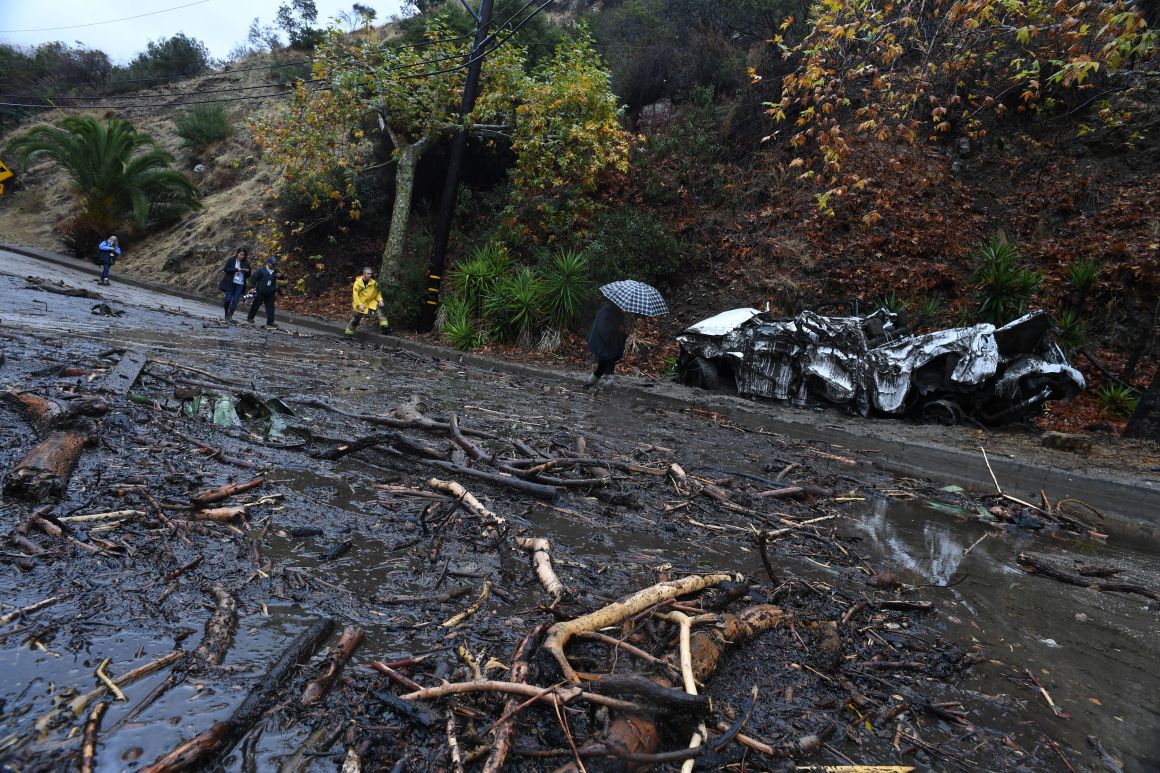 A firefighter instructs journalists to retreat to safer ground after a rain-driven mudslide destroyed two cars and damaged property in a neighborhood under mandatory evacuation in Burbank, California, January 9th, 2018.