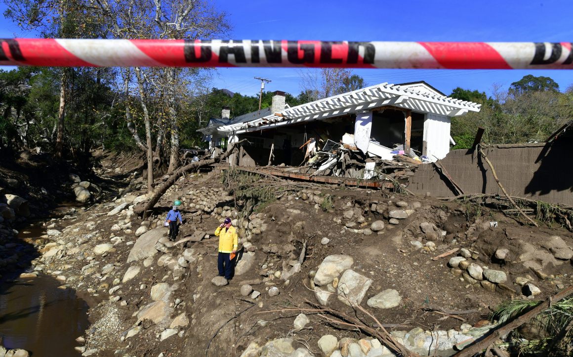 Rescue workers walk amid the debris of damaged property from mudflows carrying boulders, rocks, and uprooted trees in Montecito, California, on January 12th, 2018.