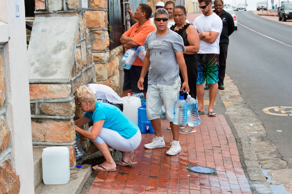 People collect drinking water from pipes fed by an underground spring, in St. James, about 25km from Cape Town's city center, on January 19th, 2018.