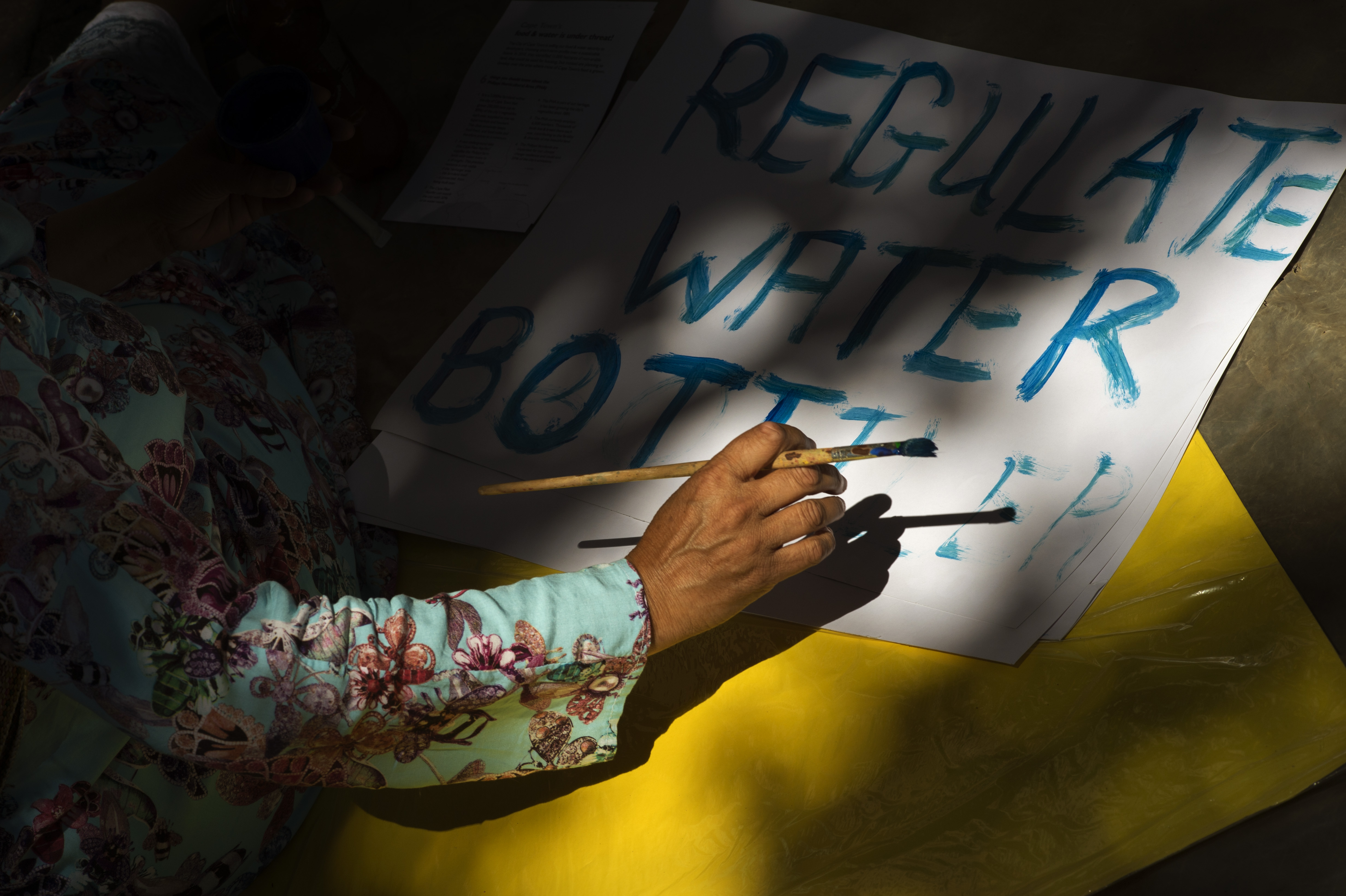 A woman writes on a placard on January 28th, 2018, prior to a protest in Cape Town, South Africa, against the means by which the city council has dealt with water shortages.