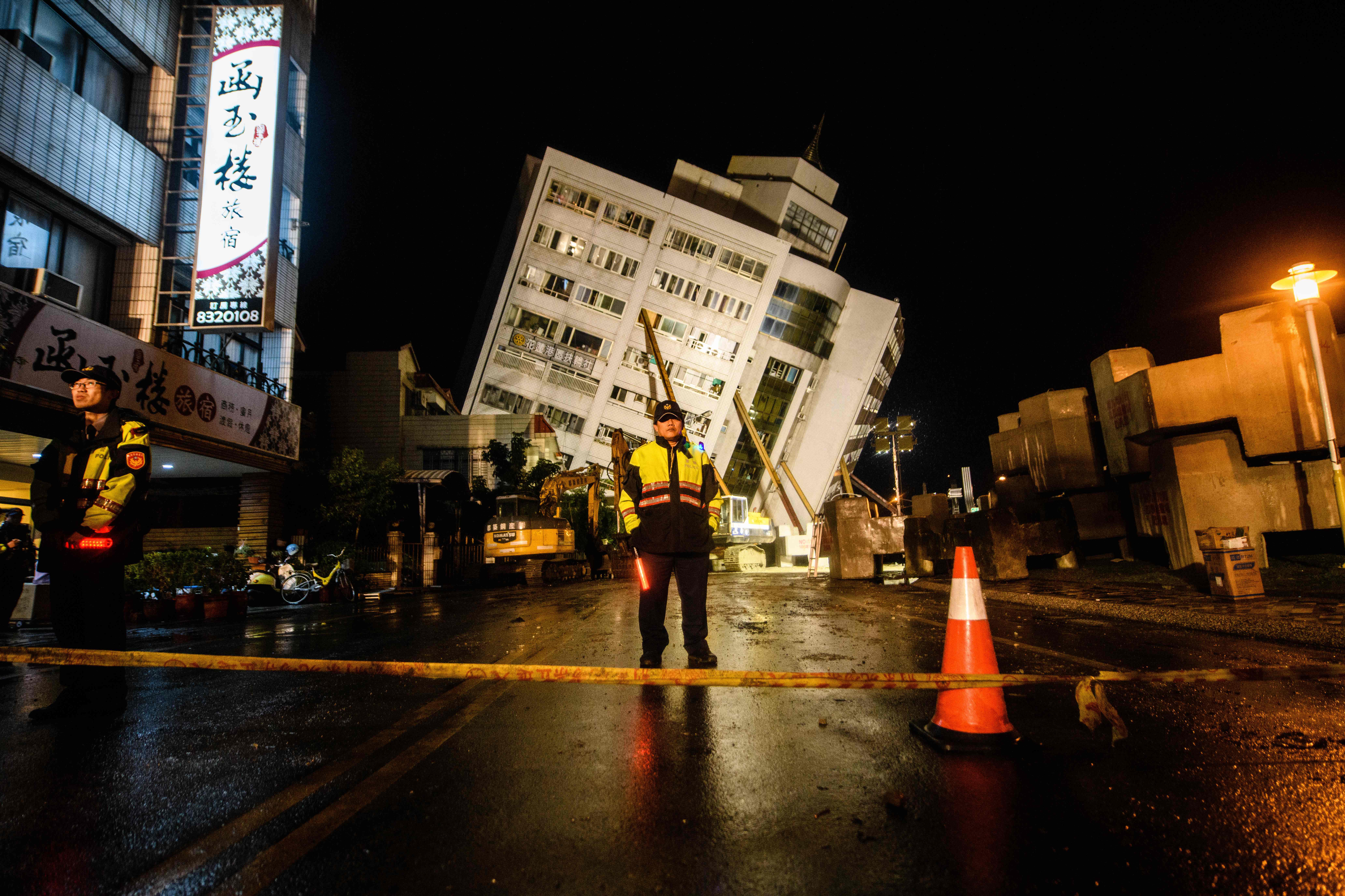 Rescue workers stand guard in front of a cordon as the Yun Tsui apartment building leans to one side after an overnight earthquake in Hualien, Taiwan, on February 7th, 2018.