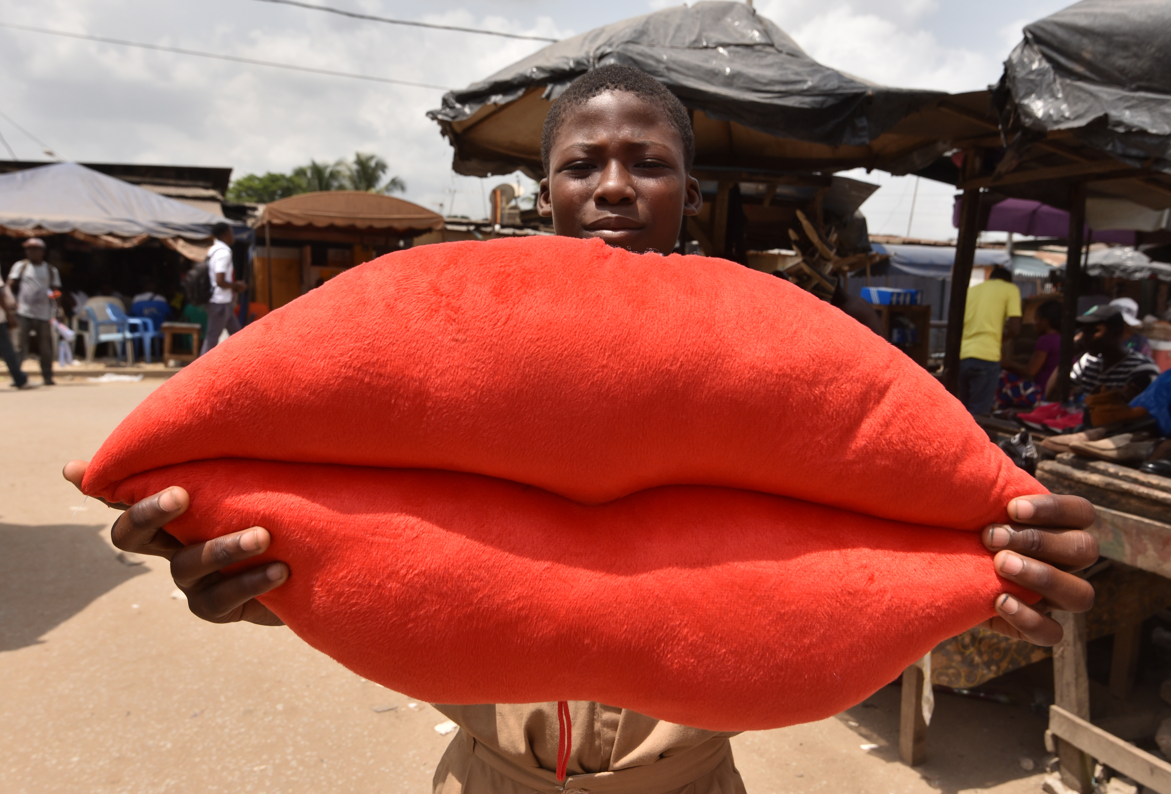 A boy poses with a pillow shaped like lips on sale for Valentine's Day in Yopougon, Ivory Coast, on February 13th, 2018.