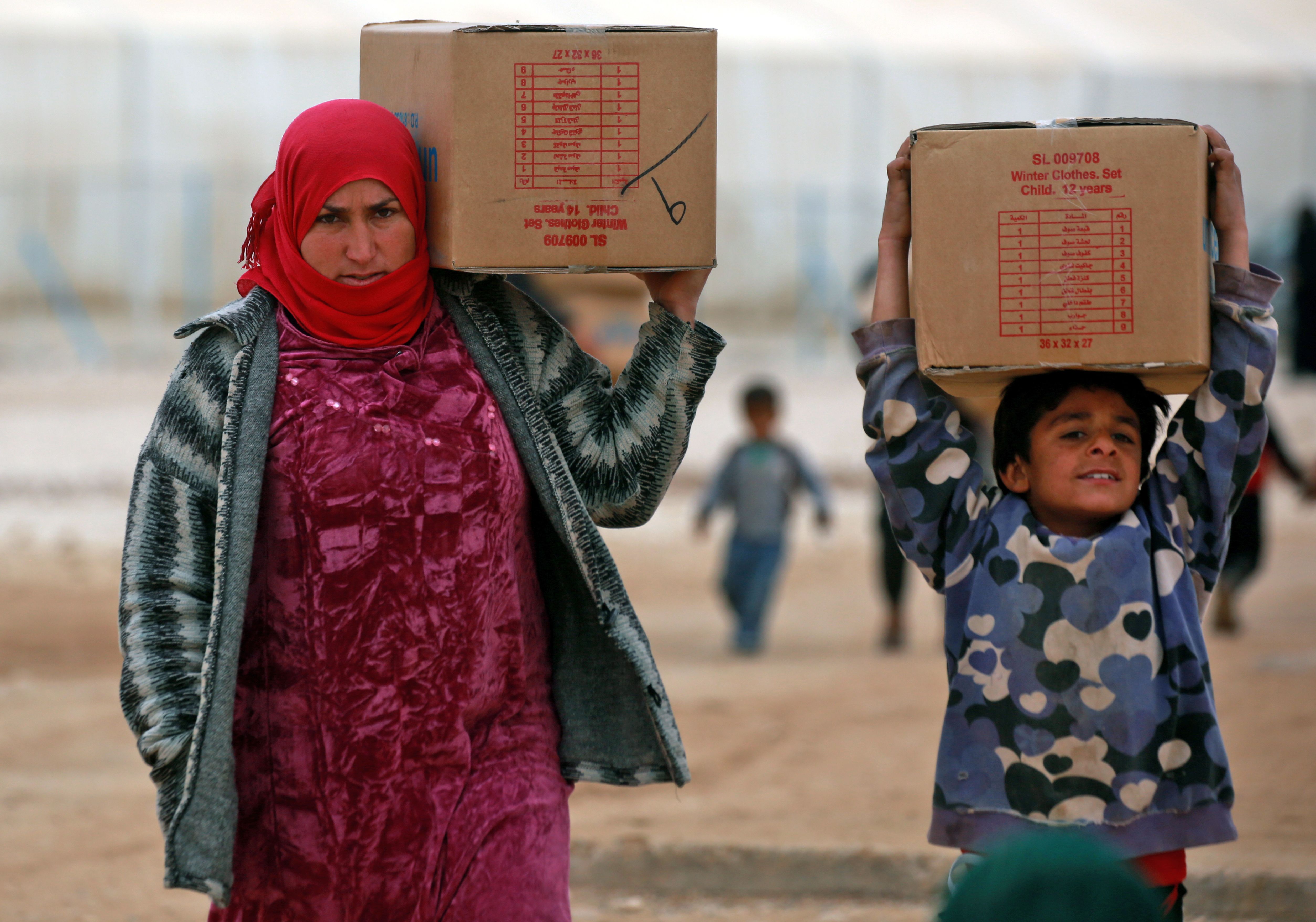 Displaced Syrians, who fled their homes in the eastern Syrian city of Deir Ezzor, carry boxes of humanitarian aid supplied by the United Nations Children's Fund at a refugee camp in Syria's northeastern Hassakeh province on February 26th, 2018.