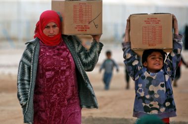 Displaced Syrians, who fled their homes in the eastern Syrian city of Deir Ezzor, carry boxes of humanitarian aid supplied by the United Nations Children's Fund at a refugee camp in Syria's northeastern Hassakeh province on February 26th, 2018.