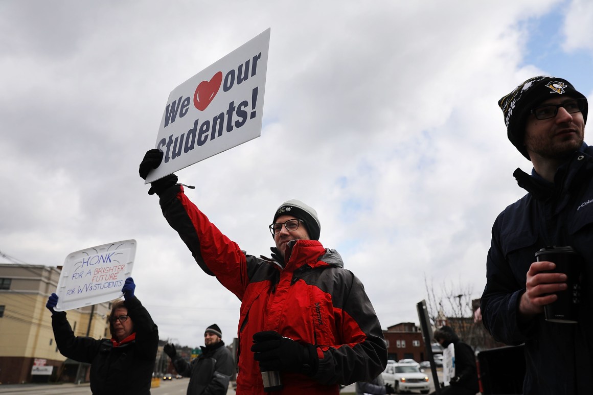 West Virginia teachers hold signs on a Morgantown street as they continue their strike on March 2nd, 2018, in Morgantown, West Virginia.