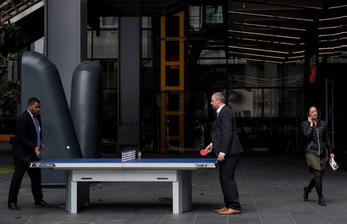 A woman walks past two men playing table tennis outside the Leadenhall Building as the deadline nears for companies to report their gender pay gap on April 4th, 2018, in London, England.