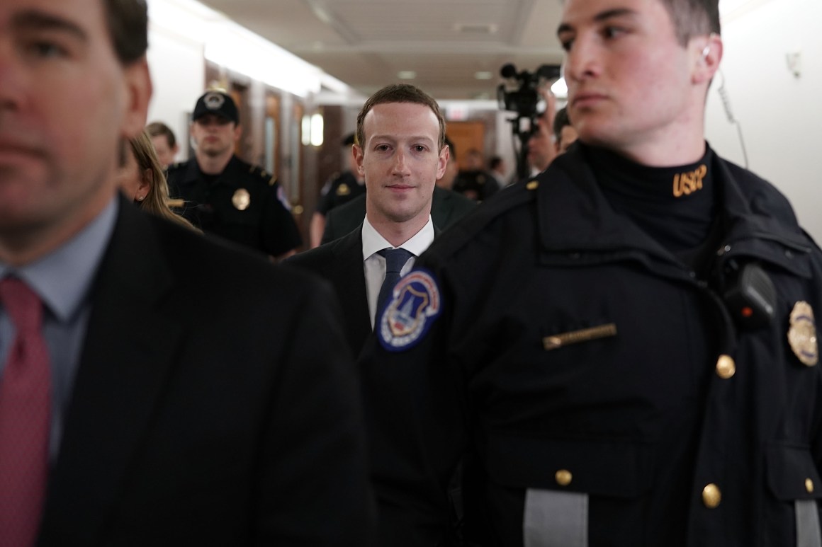 Mark Zuckerberg is escorted through the United States capitol.