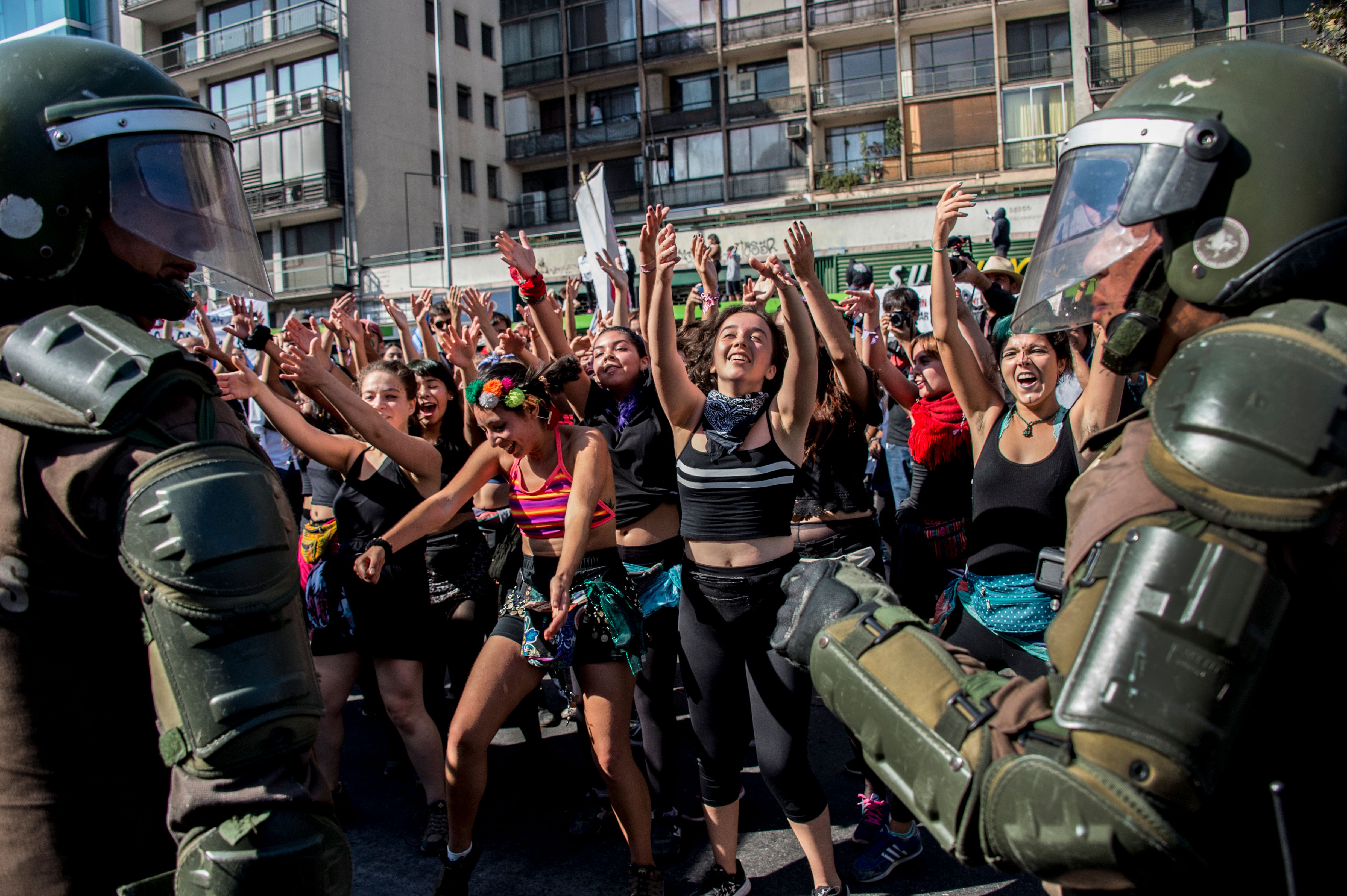 Students dance in front of riot police as they march to protest against the slowness in the progress of the Chilean education reform in Santiago on April 19th, 2018. Last month, Chile's constitutional court struck down a law that would have banned universities operating for profit, dealing a blow to free tuition reforms brought in by former leftwing president Michelle Bachelet. In a 6–4 decision, the court's judges sided with a group of private universities that challenged the measure as unconstitutional.