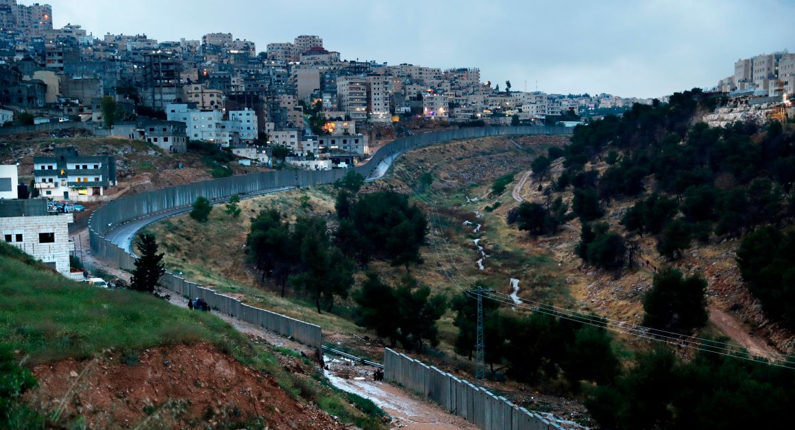 Palestinians from the Shuafat refugee camp stand on part of the separation wall on April 26th, 2018, after it collapsed due to heavy rainfall and floods.