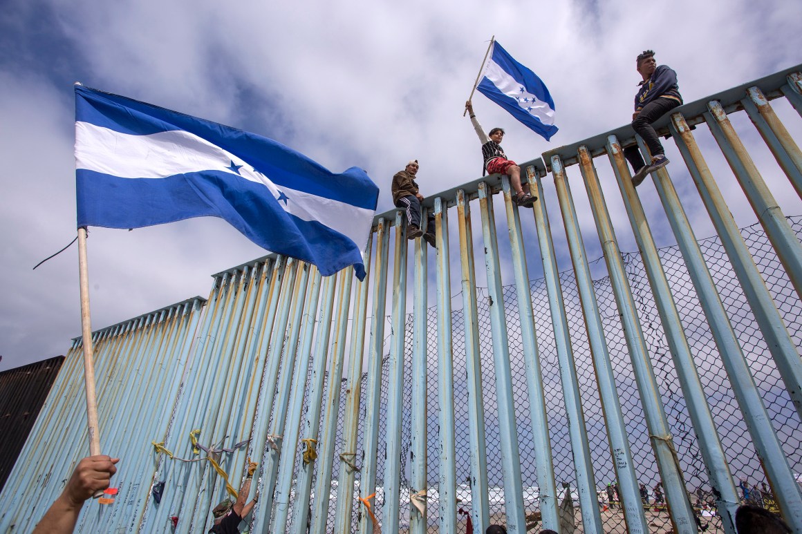 People hold Honduran flags at the border fence during a rally with members of a caravan of Central American asylum seekers and supporters on April 29th, 2018, in Tijuana, Mexico.