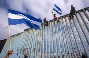 People hold Honduran flags at the border fence during a rally with members of a caravan of Central American asylum seekers and supporters on April 29th, 2018, in Tijuana, Mexico.