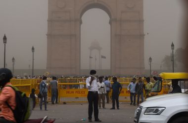 An Indian traffic policeman covers his face as he stands on duty during a dust storm in New Delhi on May 2nd, 2018.