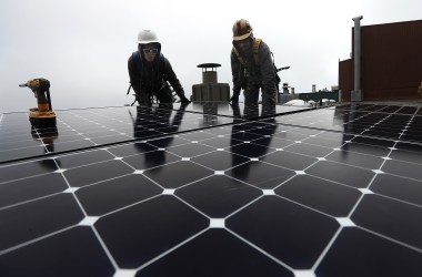 Workers install solar panels on the roof of a home on May 9th, 2018, in San Francisco, California.