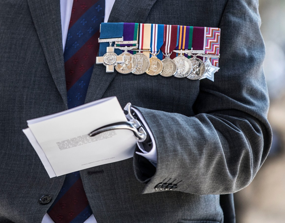 Major Peter Norton GC grips a program in his prosthetic hand as he waits to greet Prince Charles, Prince of Wales (not seen) at the door as he attends the bi-annual service of the Victoria Cross and George Cross Association at St Martin-in-the-Fields on May 15th, 2018, in London, England. Major Norton lost an arm and a leg while leading an EOD team in Iraq in 2005.