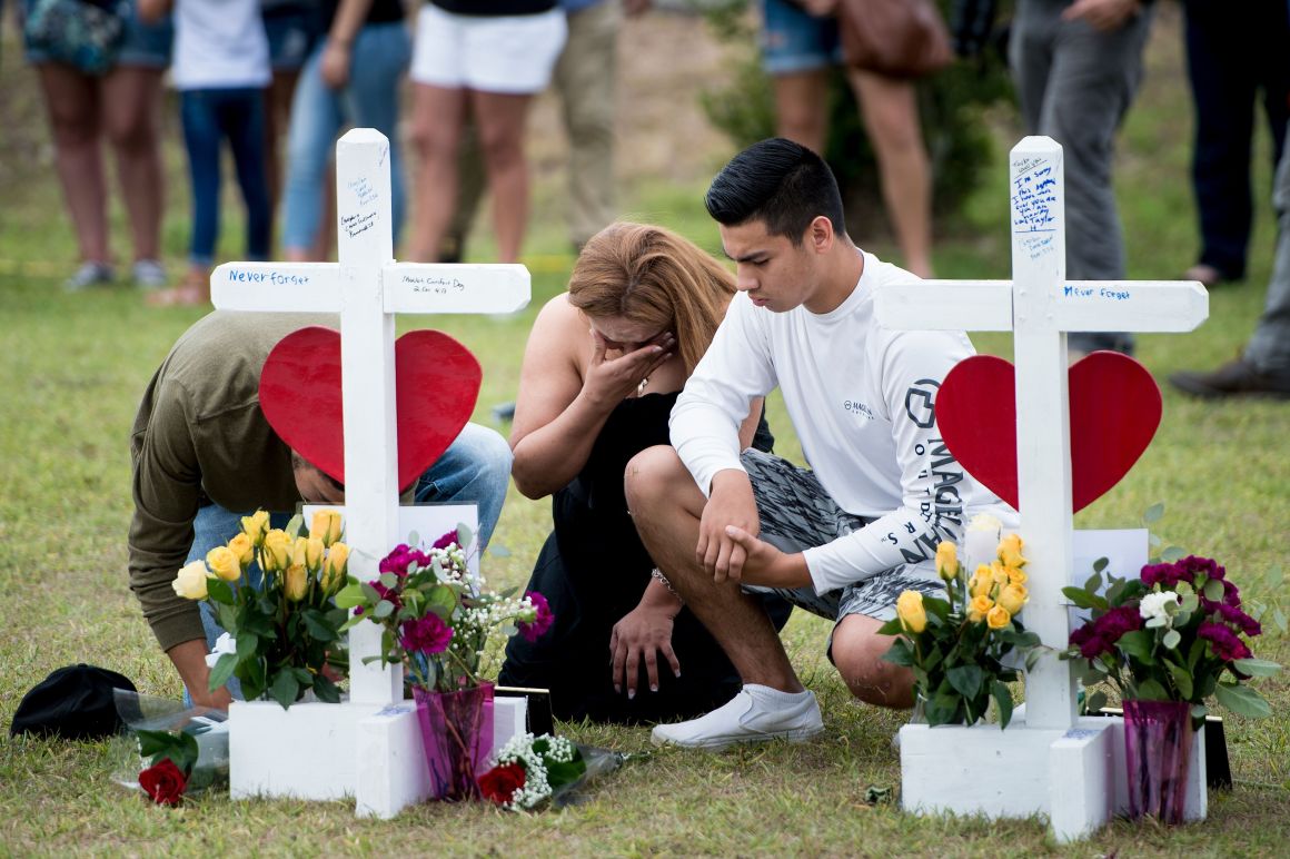 People visit a cross for Christopher Stone at a memorial for the victims of the Santa Fe High School shooting on May 21st, 2018, in Santa Fe, Texas.