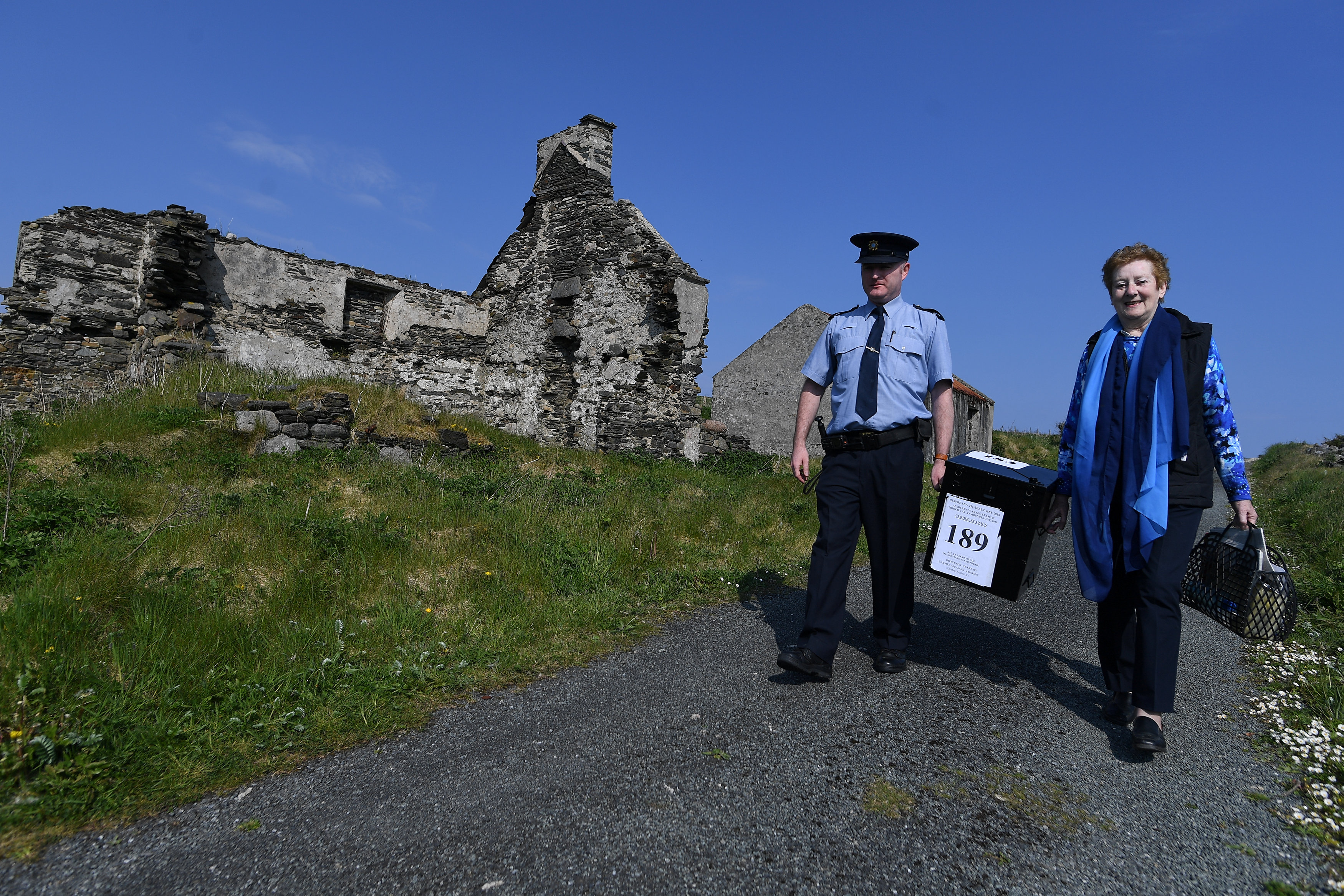 Presiding Officer Carmel McBride and Garda Alan Gallagher carry the polling box for the referendum on liberalizing abortion law a day early onto the Donegal coastal island of Inishbofin, Ireland, on May 24th, 2018.