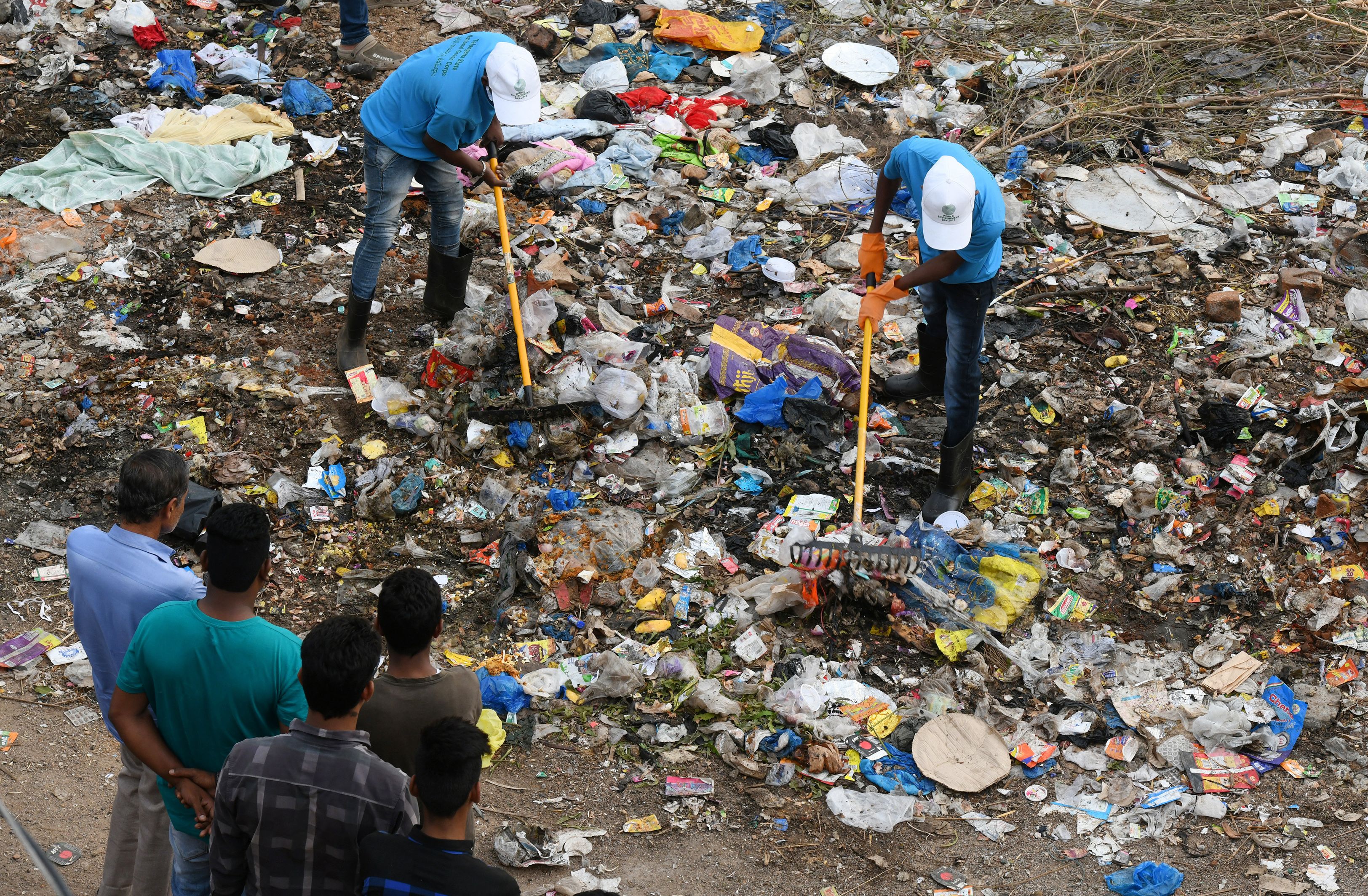 Indian residents look on as members of the National Green Corps clean up garbage along the Musi river in Hyderabad on June 3rd, 2018.