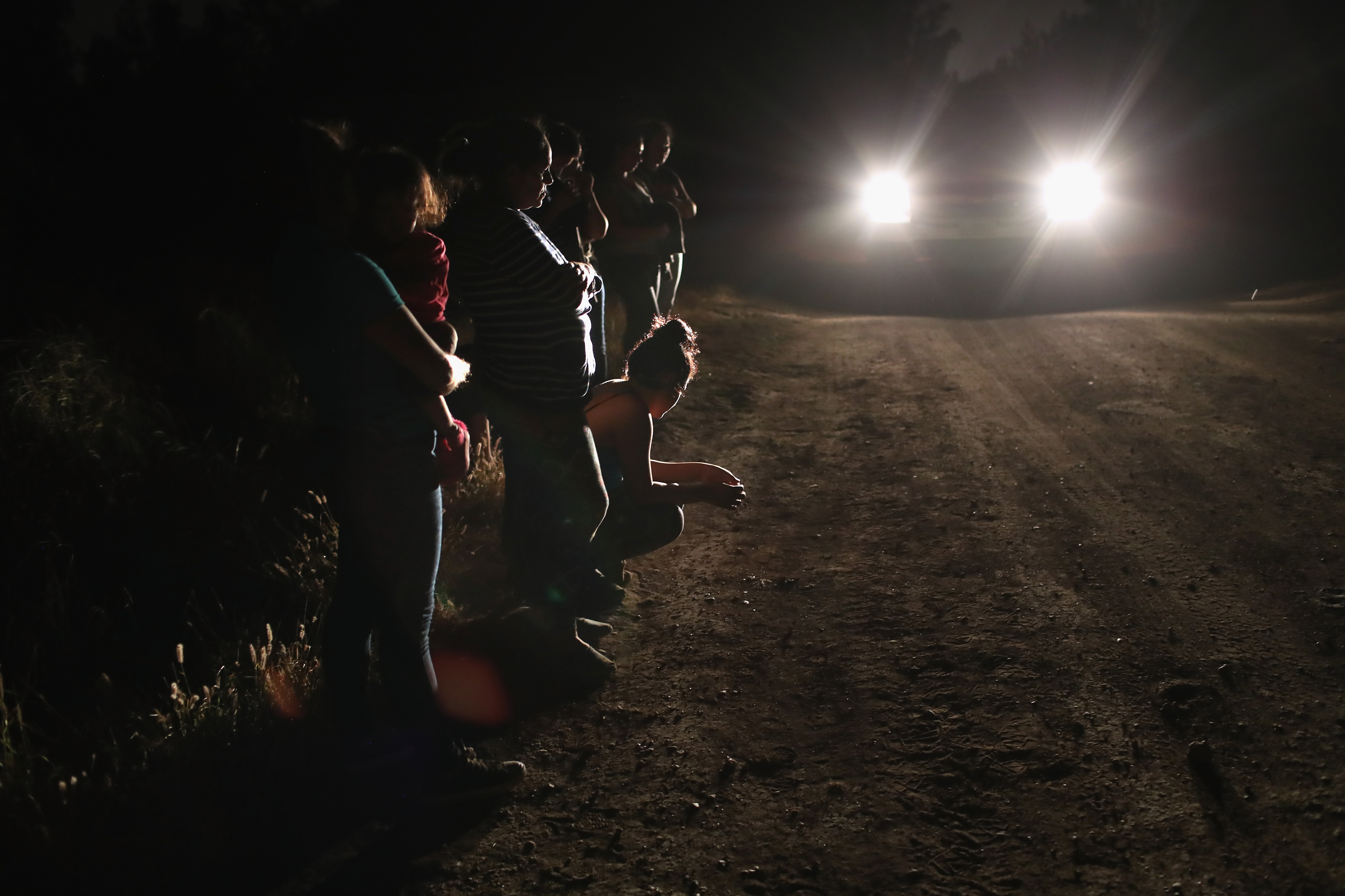 Central American asylum seekers wait for transport while being detained by U.S. Border Patrol agents near the U.S.-Mexico border on June 12th, 2018, in McAllen, Texas. The group of women and children had rafted across the Rio Grande from Mexico and were detained before being sent to a processing center for possible separation.