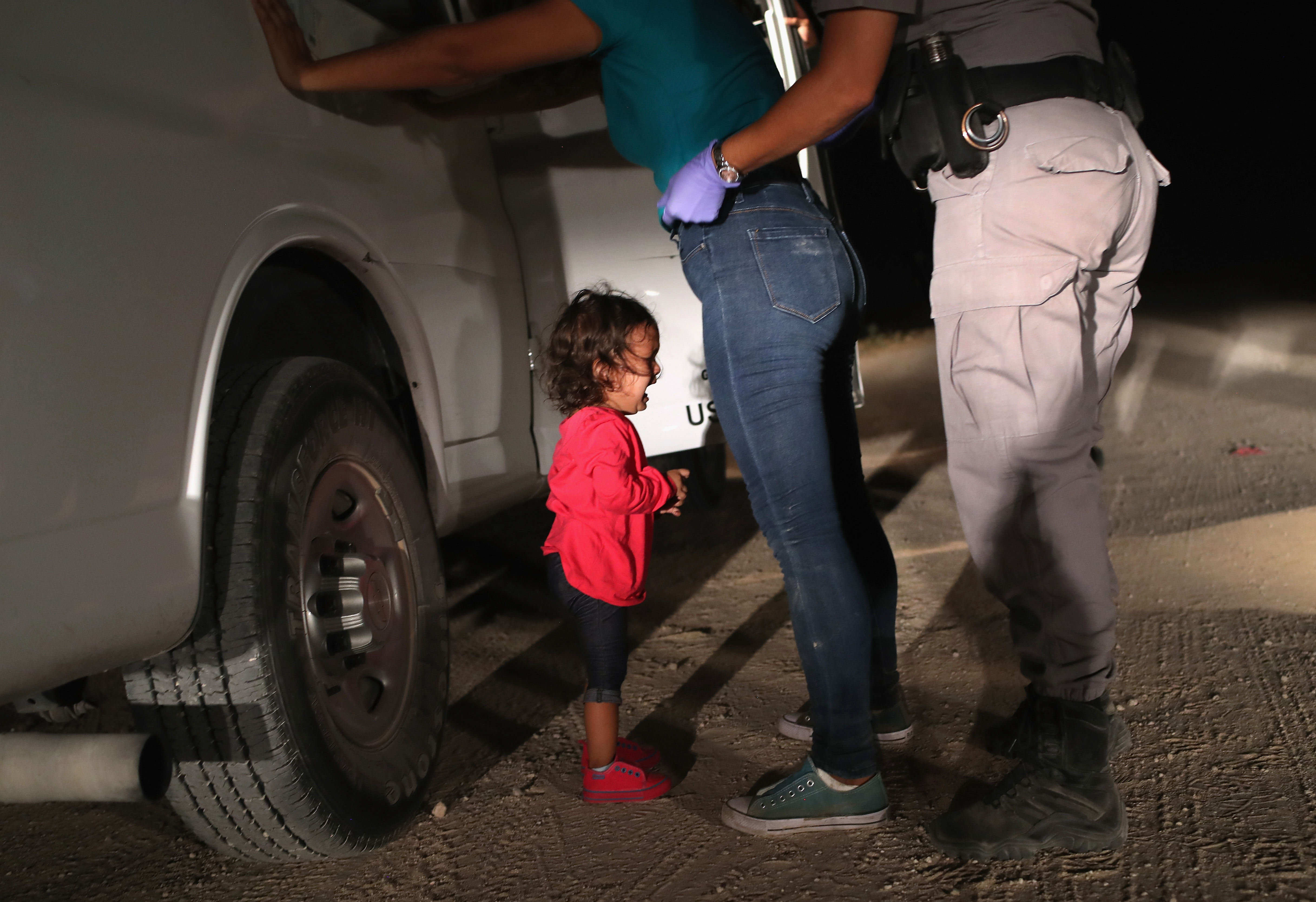 A two-year-old Honduran asylum seeker cries as her mother is searched and detained near the U.S.-Mexico border on June 12th, 2018, in McAllen, Texas. The asylum seekers had rafted across the Rio Grande from Mexico and were detained by Border Patrol agents before being sent to a processing center for possible separation.