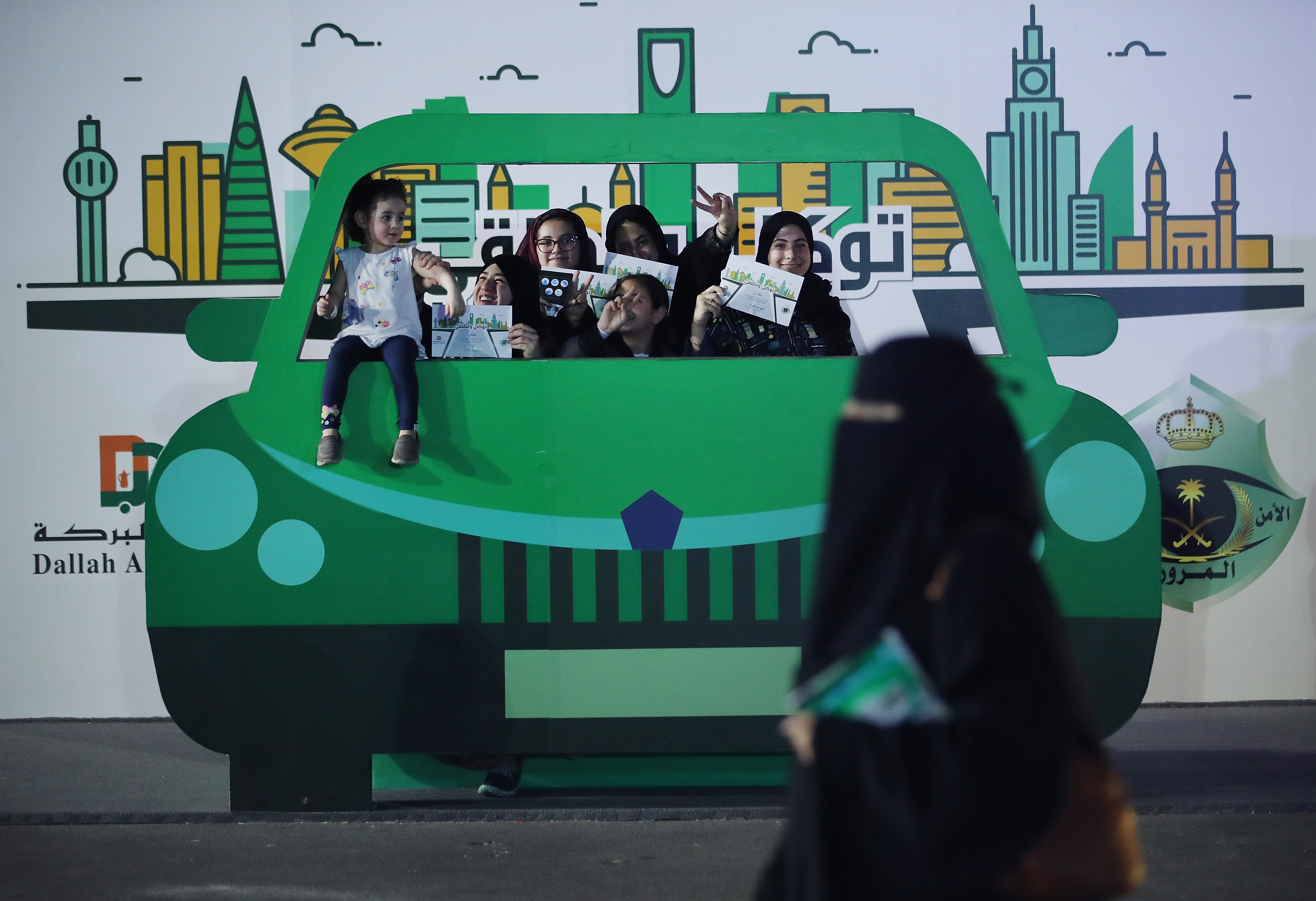 Teenage girls in Jeddah pose behind a model car on June 22nd, 2018, while holding up certificates for completing an outdoor educational driving event for women.