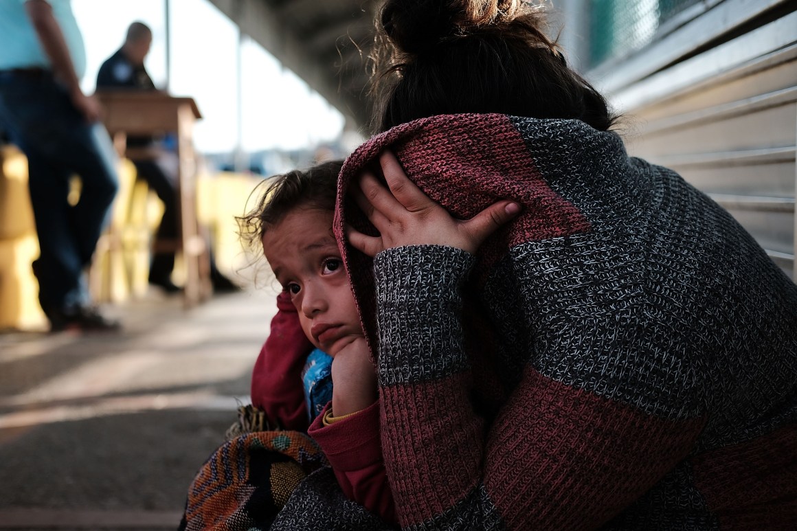 A Honduran child and her mother, fleeing poverty and violence in their home country, wait along the border bridge after being denied entry from Mexico into the U.S.