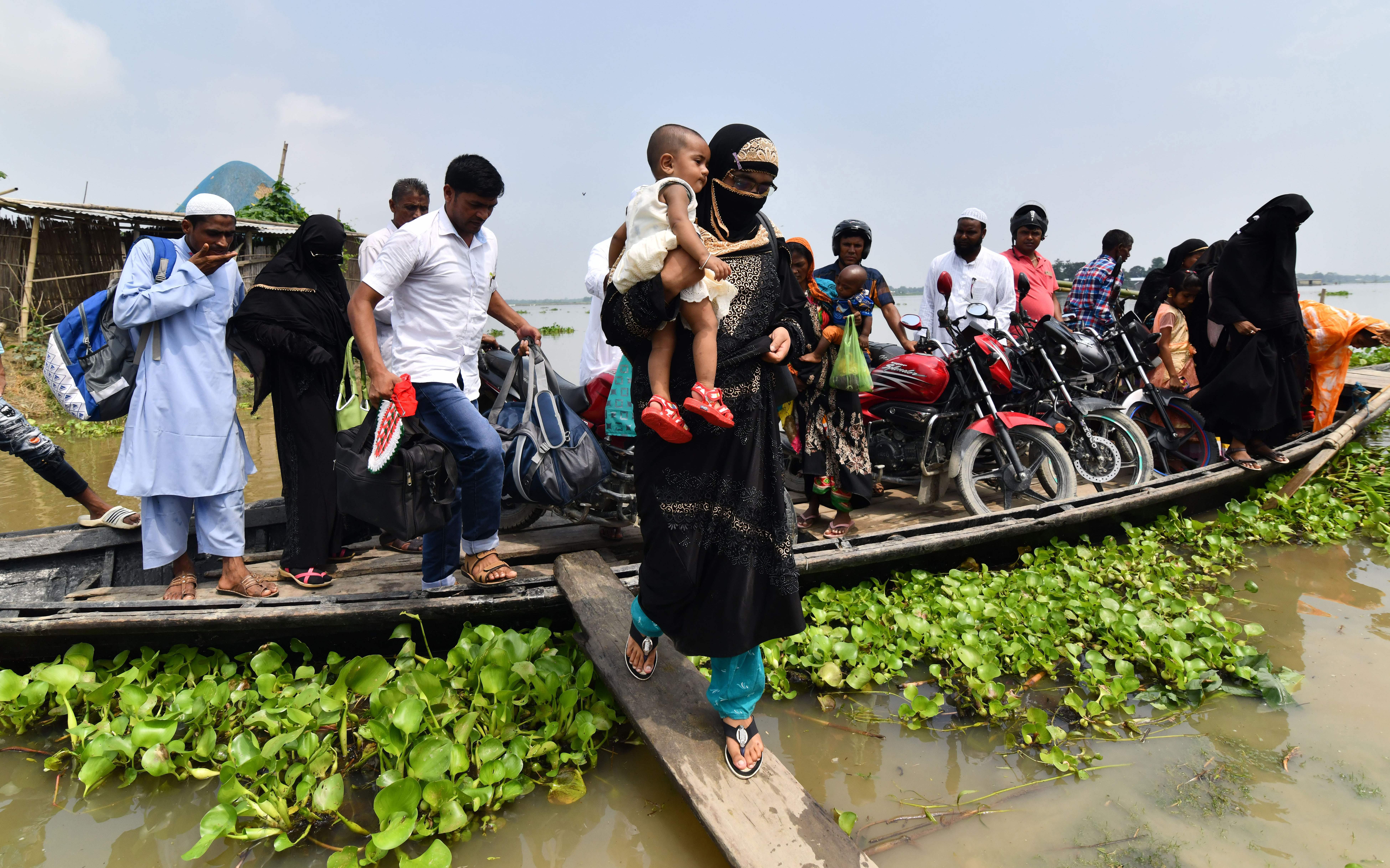 An Indian villager steps off a boat as she carries her child in flood-affected Ashigarh village in Morigoan district, in India's northeastern state of Assam, on July 6th, 2018. Heavy monsoon rains bring floods to parts of northeastern India each year, affecting the lives of millions of people.