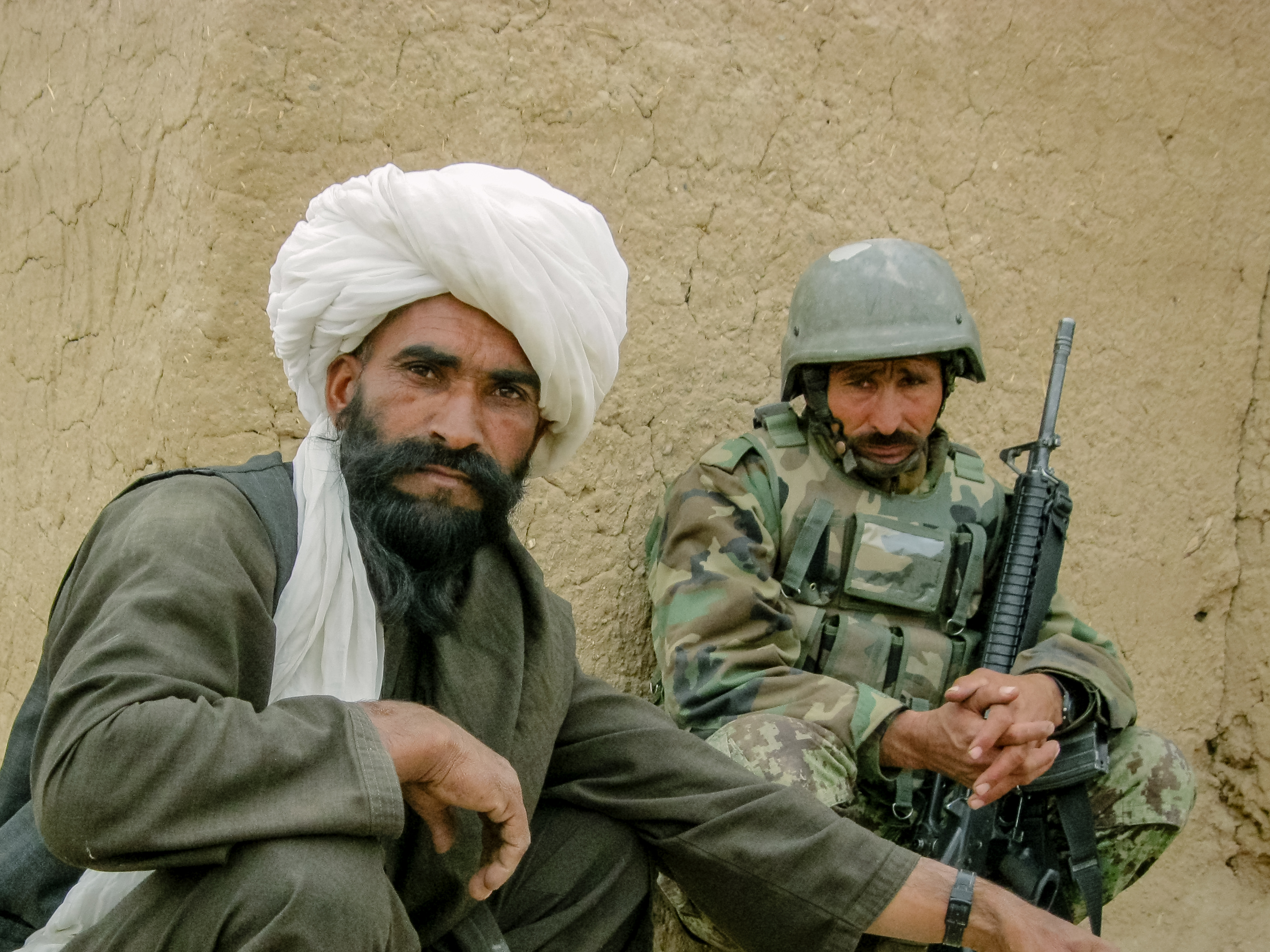 An Afghan National Army solider watches a local man have his photo taken during a patrol in the winter of 2010.