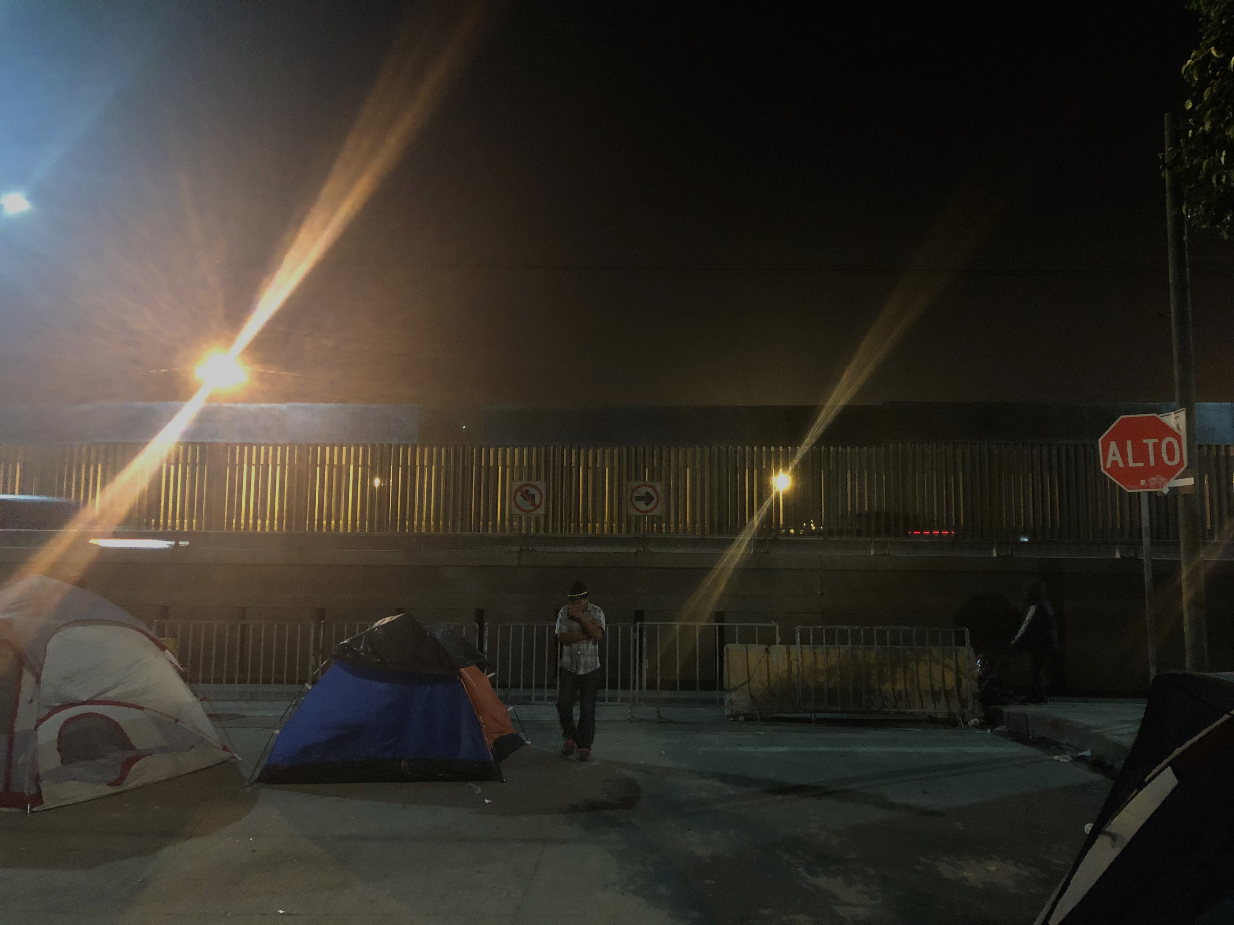 The tent village outside of the Benito Juárez sports complex in Tijuana, Mexico, straddles the border wall with the United States, visible in the background of this photo.