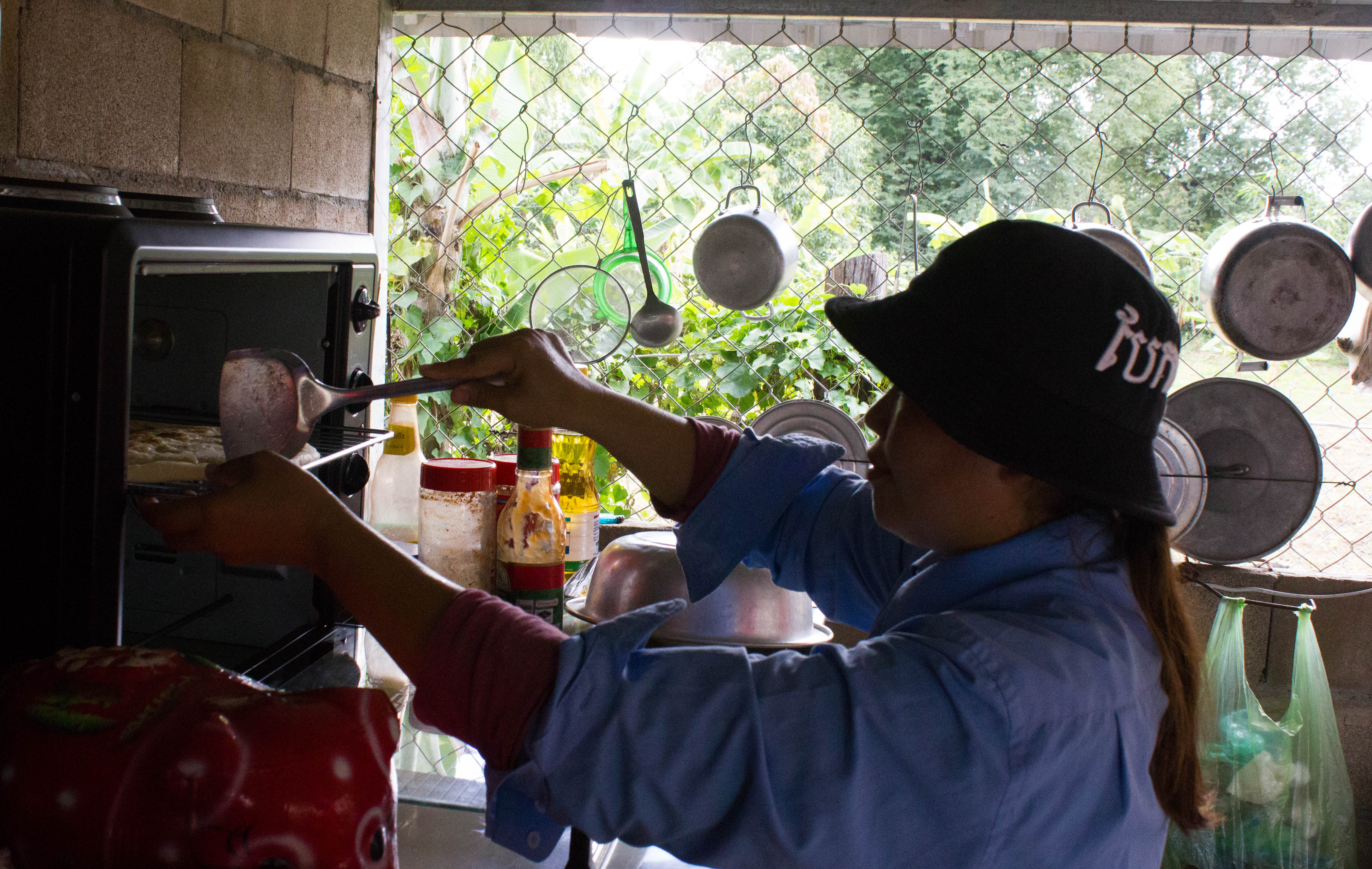 Nheb Thai’s wife, Kim Lun, making pizza in their kitchen.