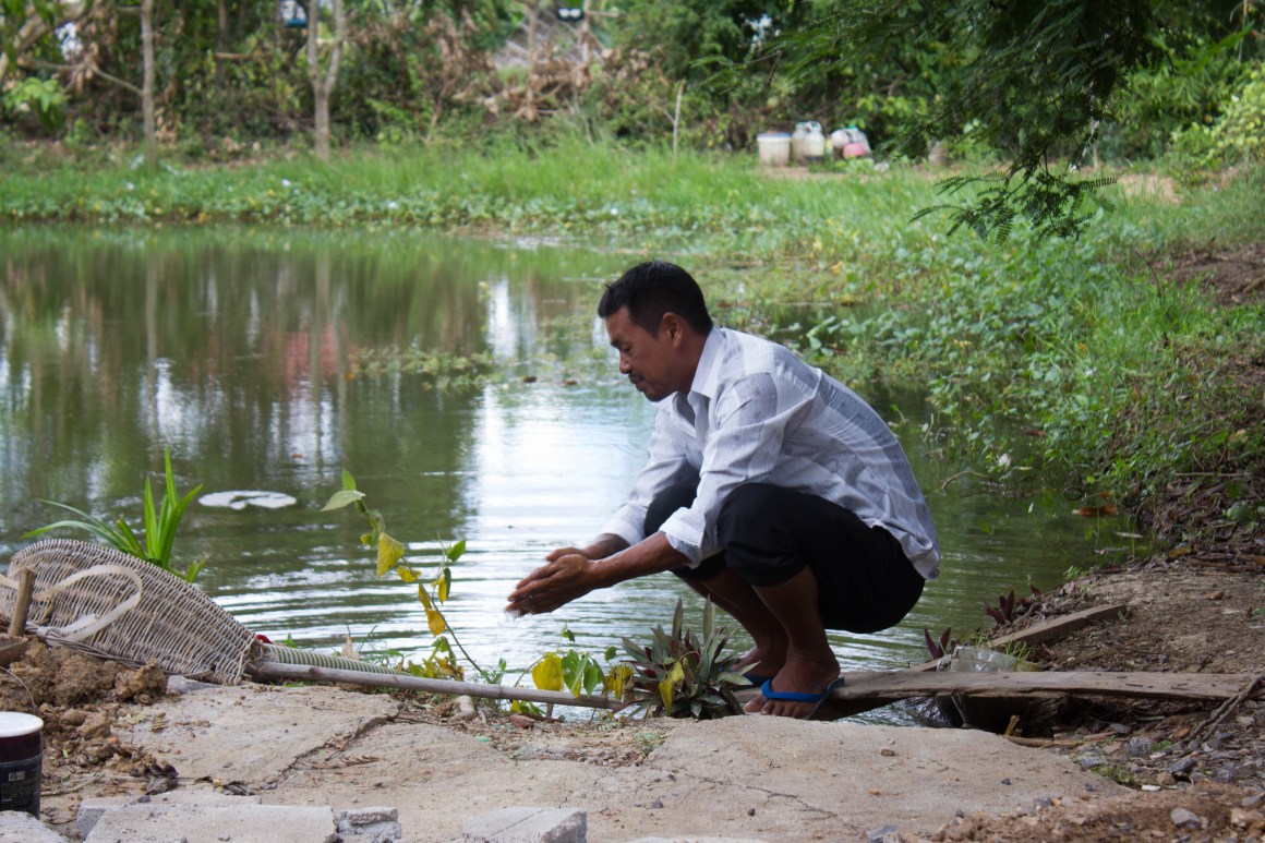 Nheb Thai washes his hand in his pond.