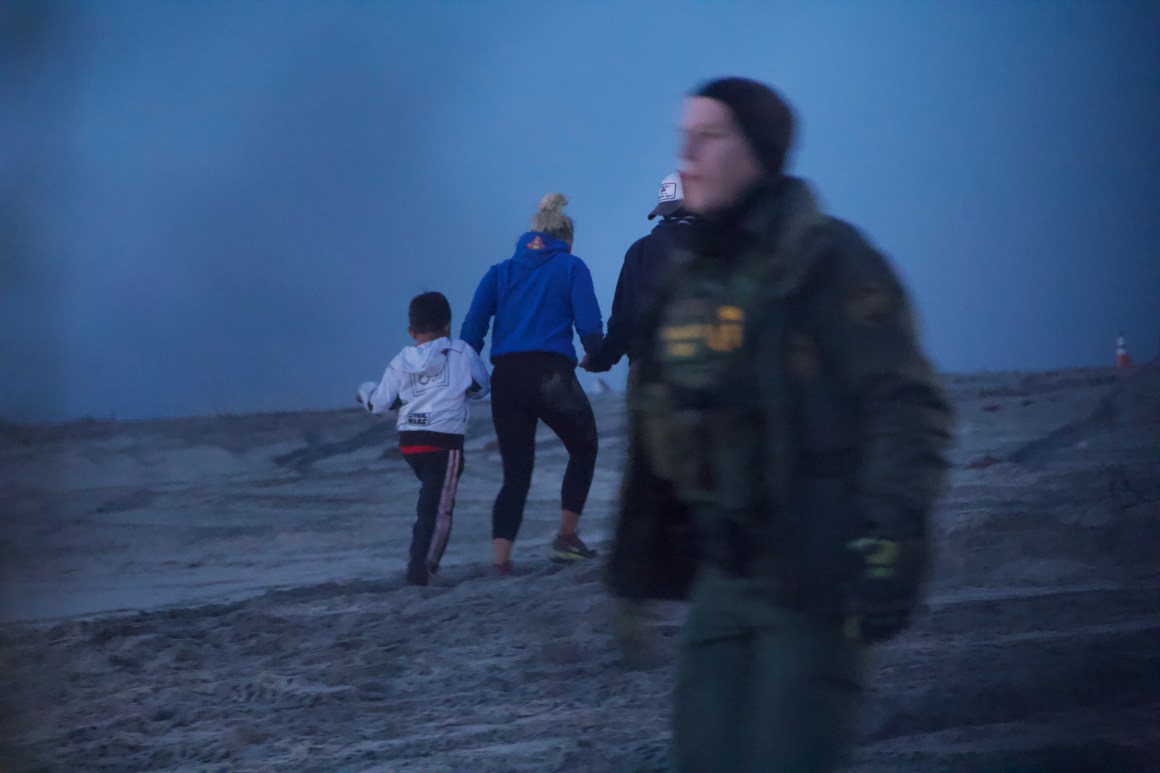 A family of three from Honduras crosses the border wall on the beach in Tijuana, Mexico, before surrendering to Border Patrol on the other side on December 13th, 2018.