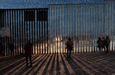 Border Patrol agents shine a light through the border wall as migrants search for a way to cross.