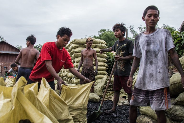 Workers manage hundreds of charcoal bags stored in a lot in Bhamo, Myanmar, before they're loaded onto trucks and bound for China.