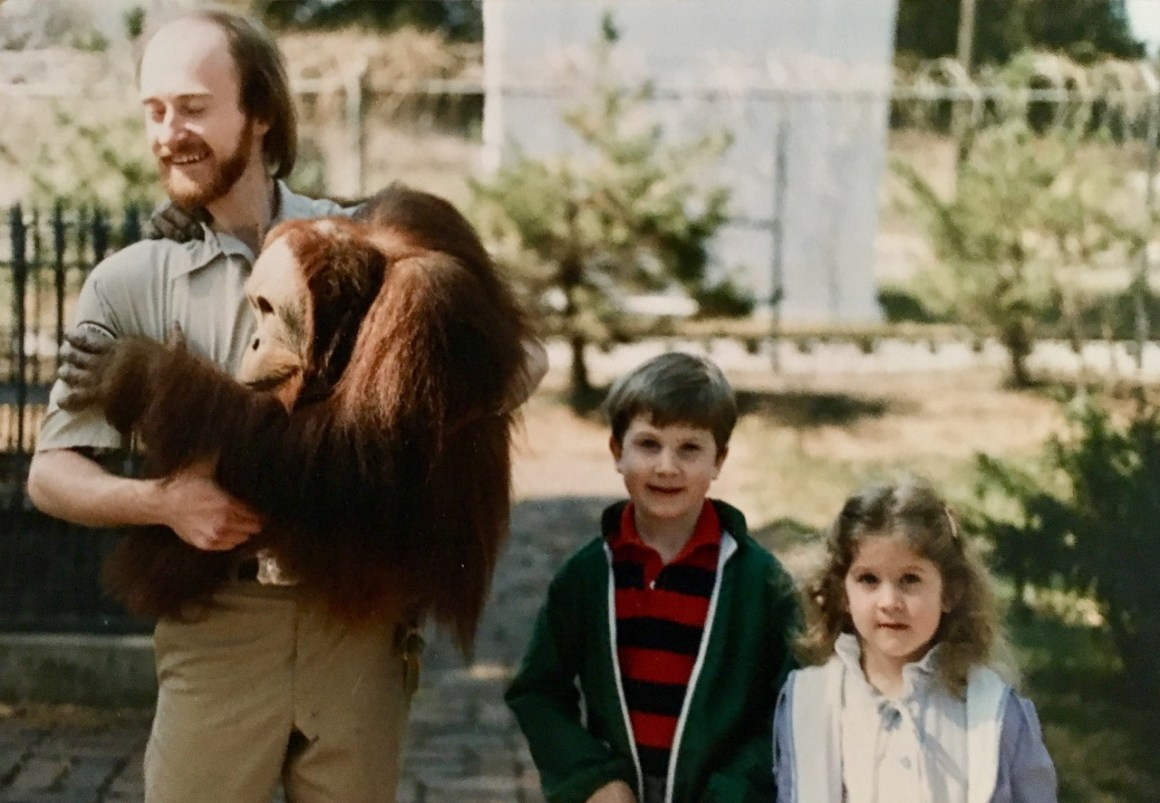 Zookeeper Dick Haskin poses for a photo with Chewy, a sumatran orangutan, and two young visitors at the Lincoln Children’s Zoo.