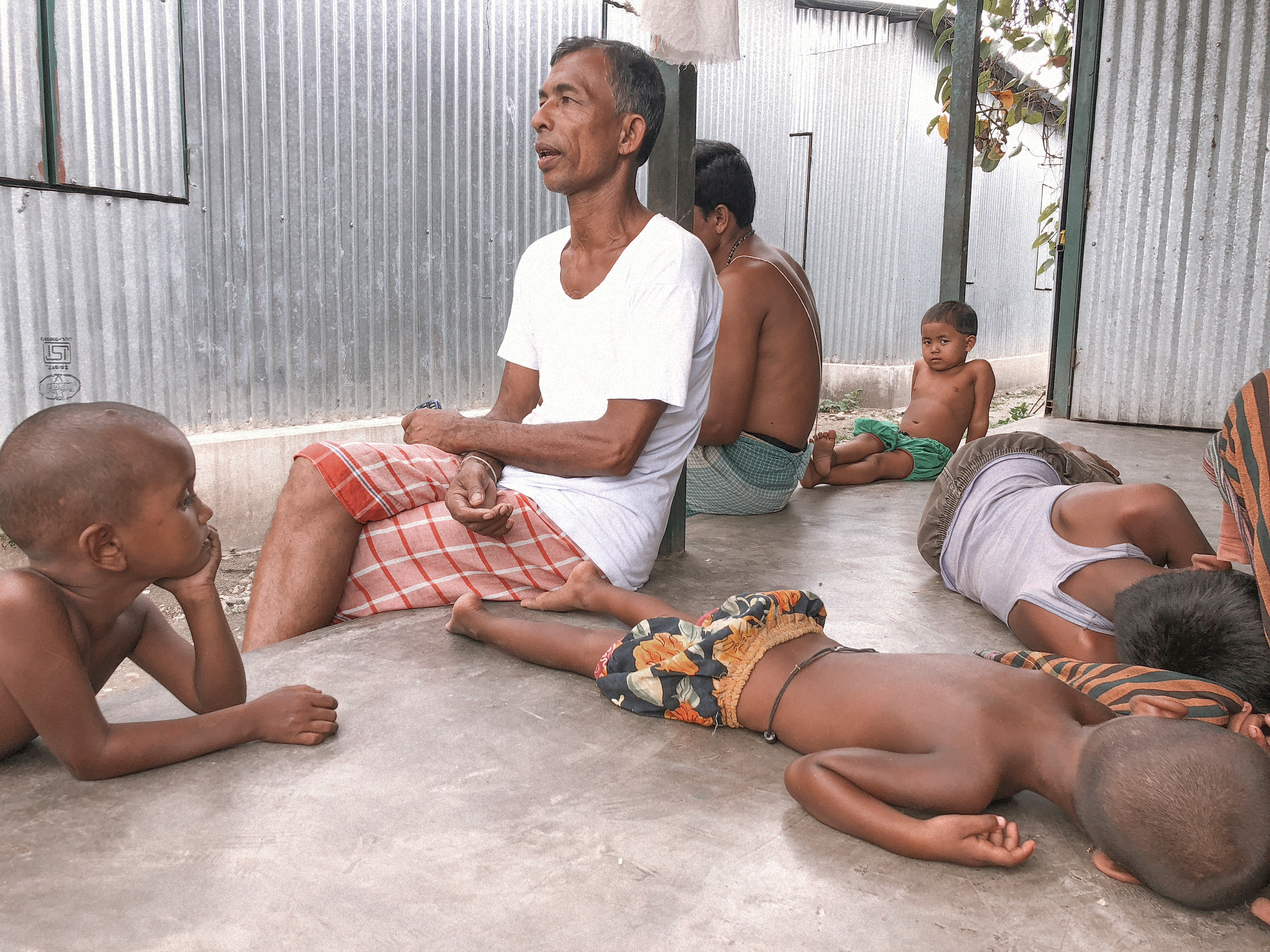 Narayan Chandra Barman laments that he left his land, property, and relatives to move to India and now has no work. The government provides families 30 kilos of rice per month but no fish or meat. Even prisoners in jail get eggs and meat, he says. His kitchen in the former chhitmahal was bigger than his entire dwelling in the resettlement camp. Since moving to India, he has not been able to visit his mother and four brothers in Bangladesh.