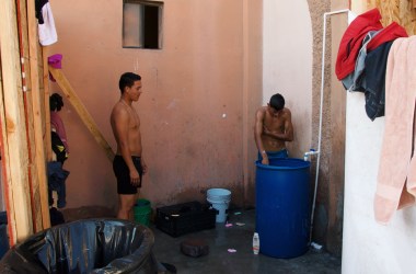 Two migrants wash in the rudimentary bathing area inside the pavilion for children and families.