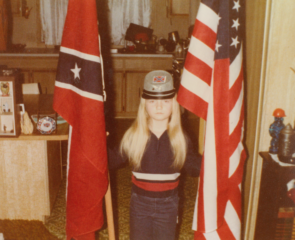 A young Jvonne Hubbard poses with American and Confederate flags.