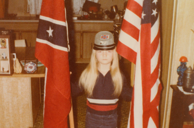 A young Jvonne Hubbard poses with American and Confederate flags.