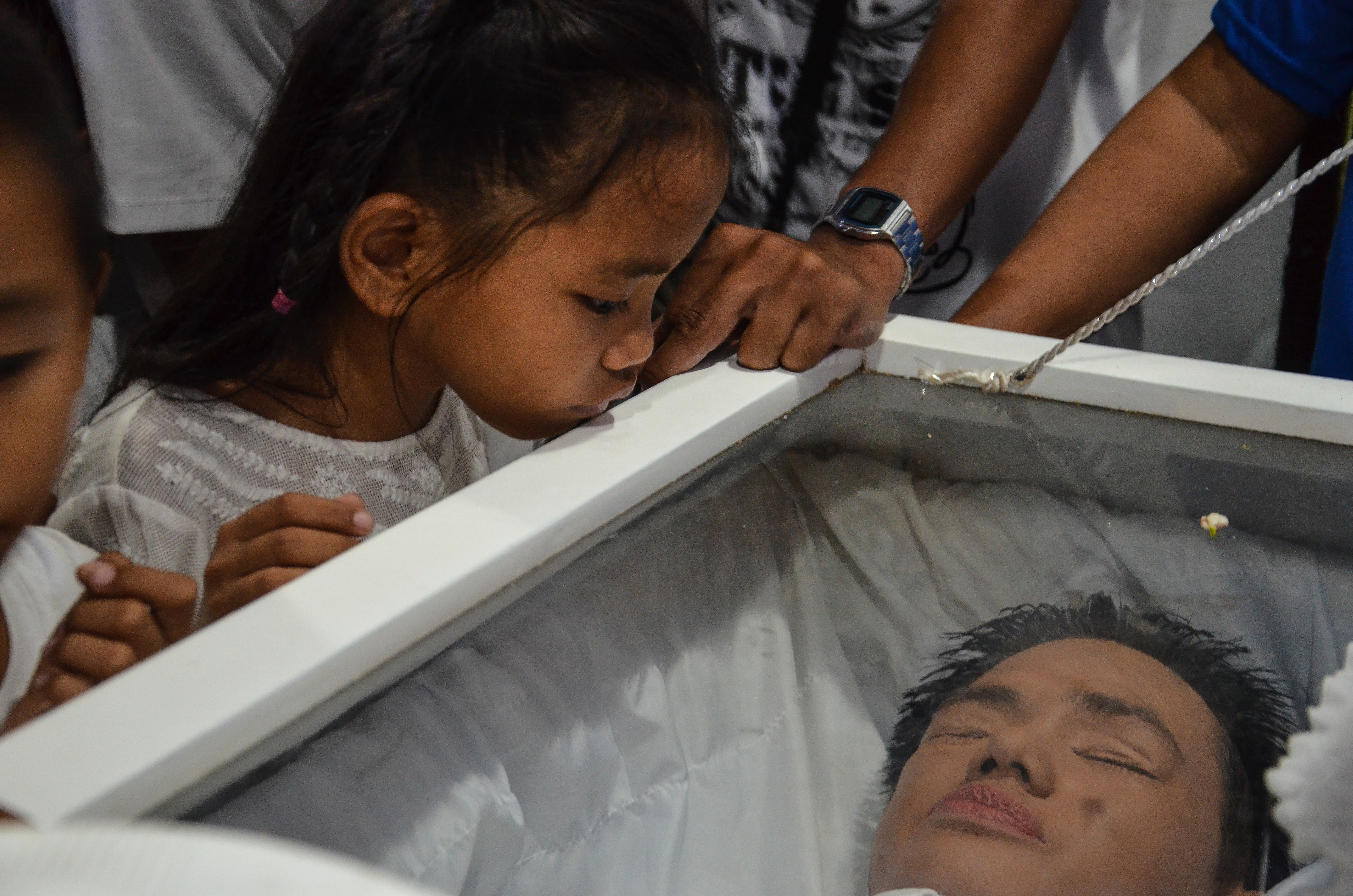 A family member looks at Enrico in his coffin at his funeral in Navotas.