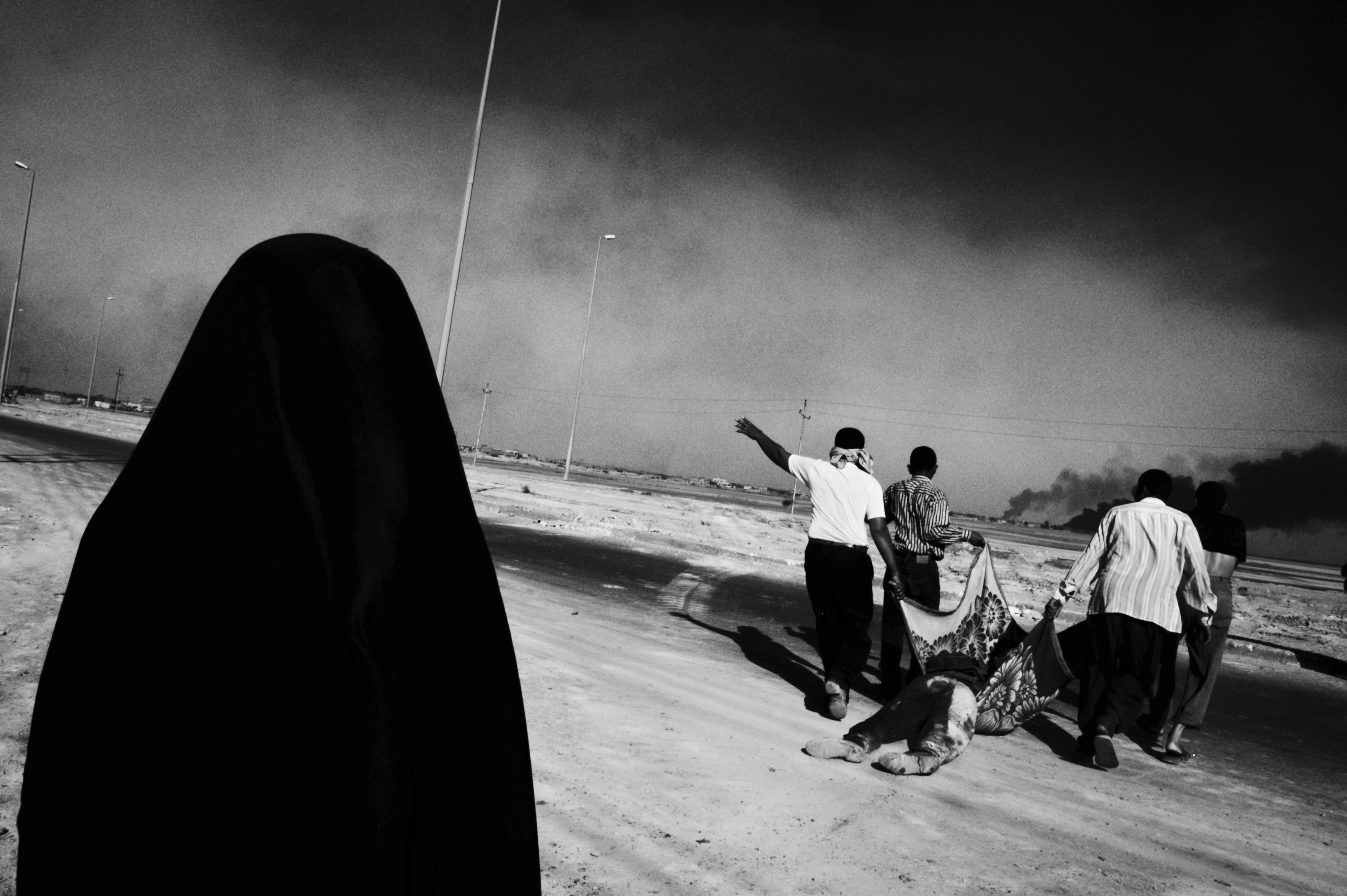 Basra, Iraq, 2003: A group of men drag a dead militant to their vehicle during the British siege of Basra.