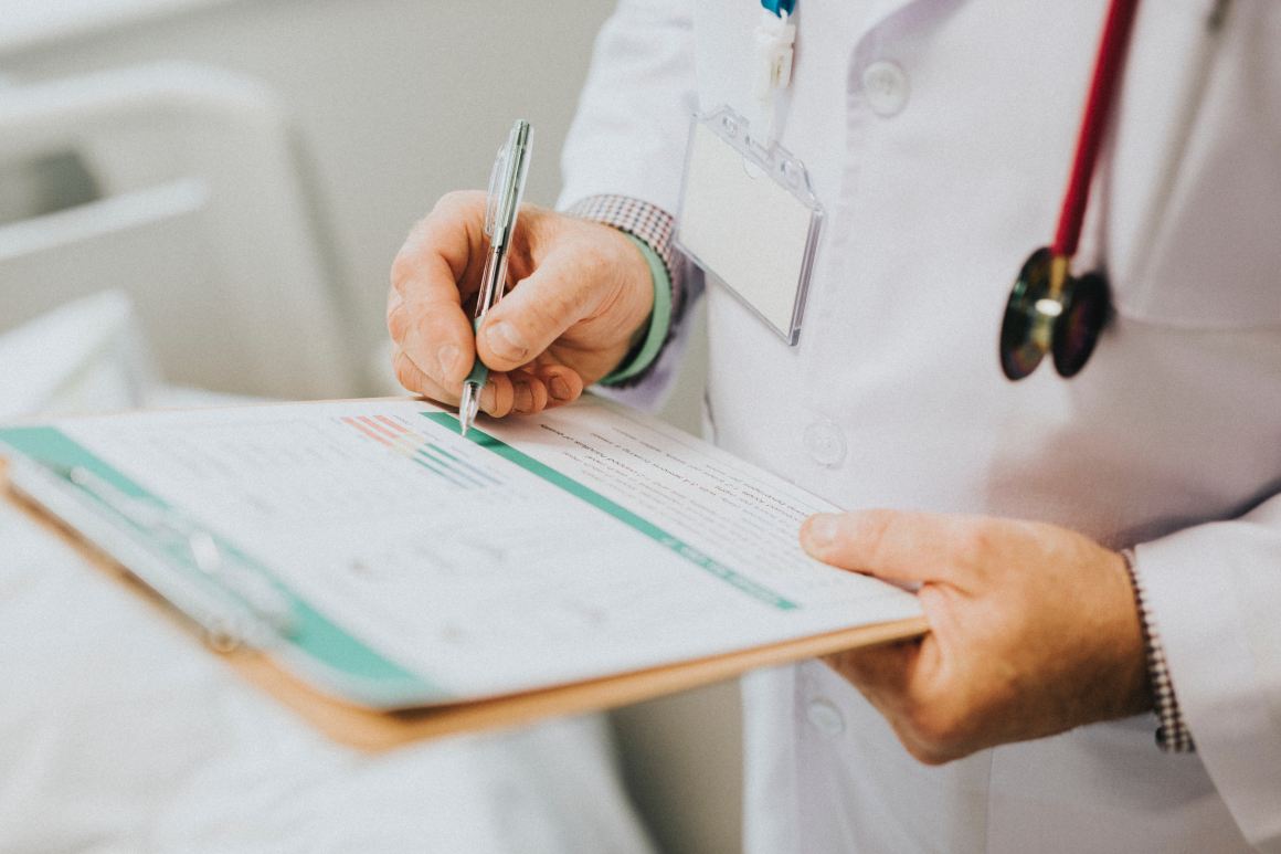 Doctor writing on paper on a clipboard.