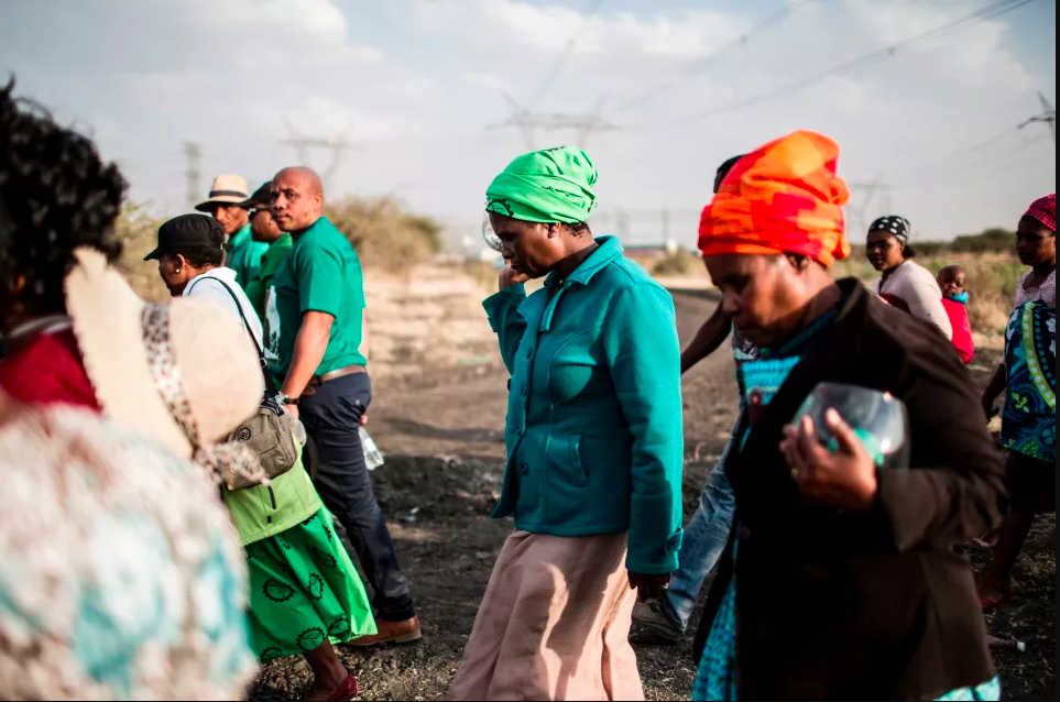 Widows of deceased striking miners who were killed during the Marikana massacre walk from the memorial site during the event's fifth anniversary in Marikana on August 16th, 2017. Thousands of South African miners sang remembrance songs at the site where police shot dead 34 strikers as campaigners demanded prosecutions and compensation. The 34 miners were gunned down after police were deployed to break up a wildcat strike that had turned violent at the Lonmin-owned Marikana platinum mine, northwest of Johannesburg.