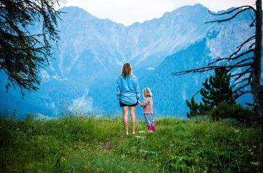 Mother and child in nature; mountain view with trees.